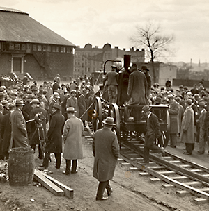 Old grainy photo of a crowd surrounding a train prototype on Stevens campus
