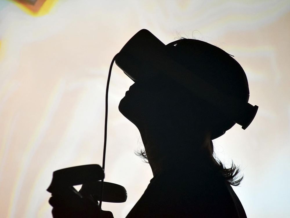 Viewer, seen in silhouette, playing Honey Fungus while wearing a VR headset