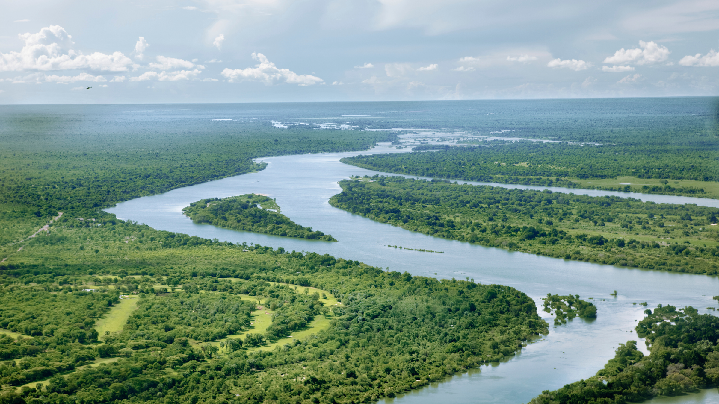 Calm rivers wind through a green, grassy landscape into the distance