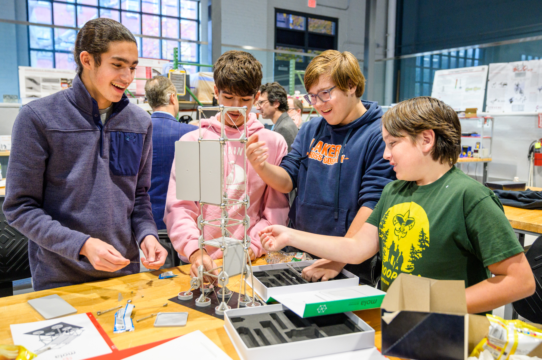 Four high school boys smile as they build a tower on a table
