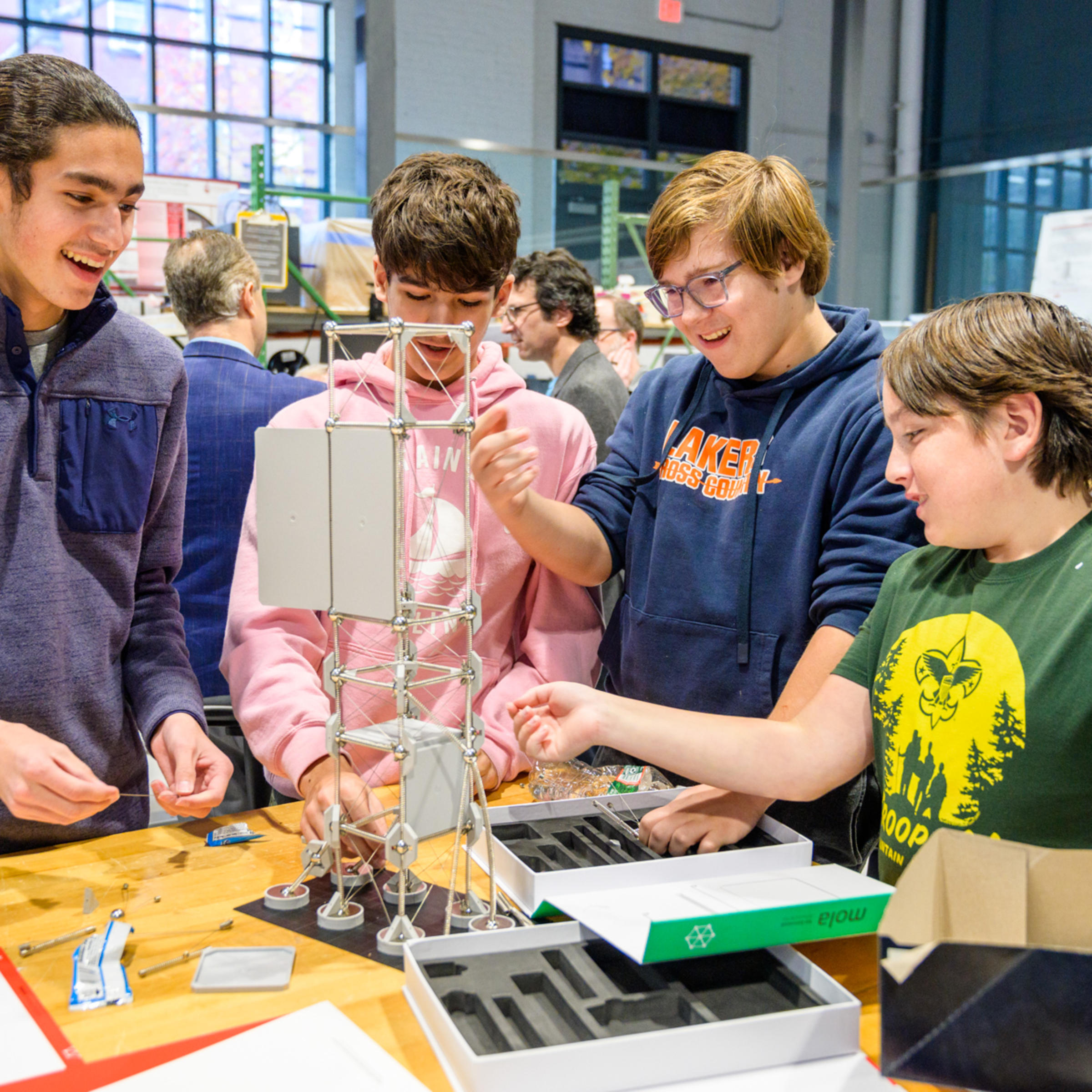 Four high school boys smile as they build a tower on a table