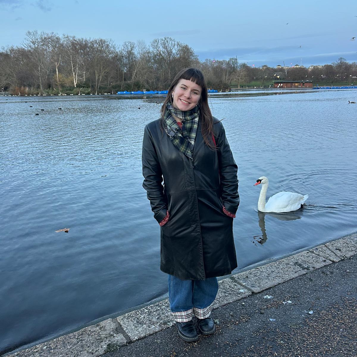 Victoria Matysiak poses in front of a lake and swan