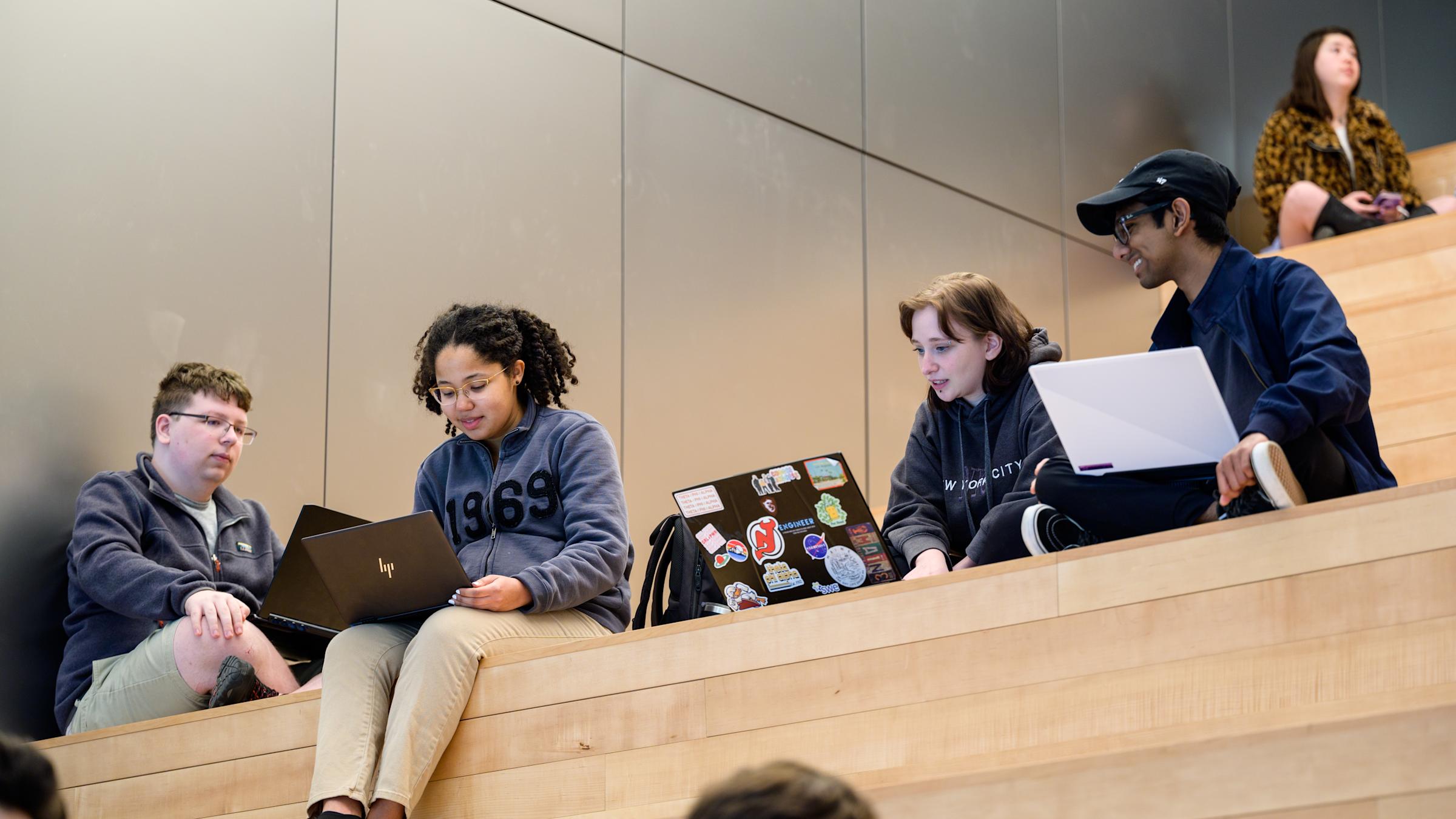 Four students studying and looking at a computer
