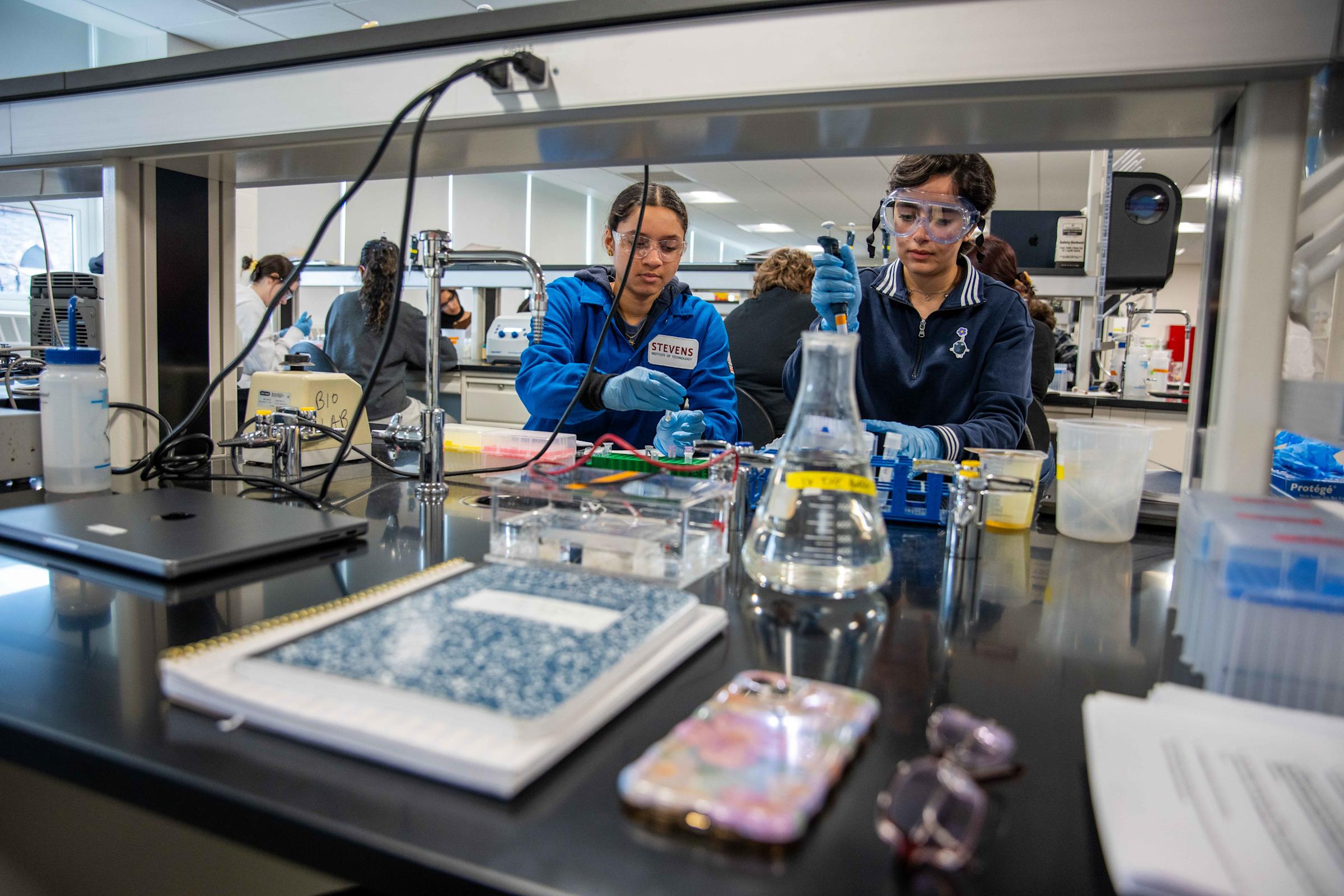 Two female students in lab gear work on a project in the newly renovated chemical biology laboratory.