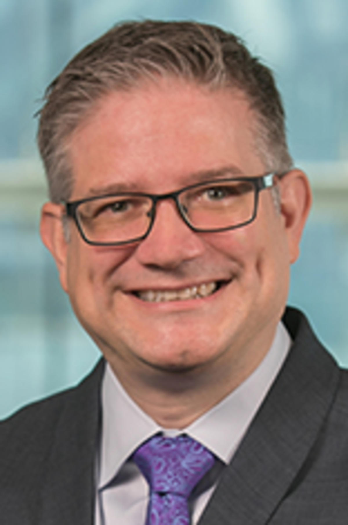 Headshot of Dr. Michael zur Muehlen in a dark suit with the New York City skyline in the background.