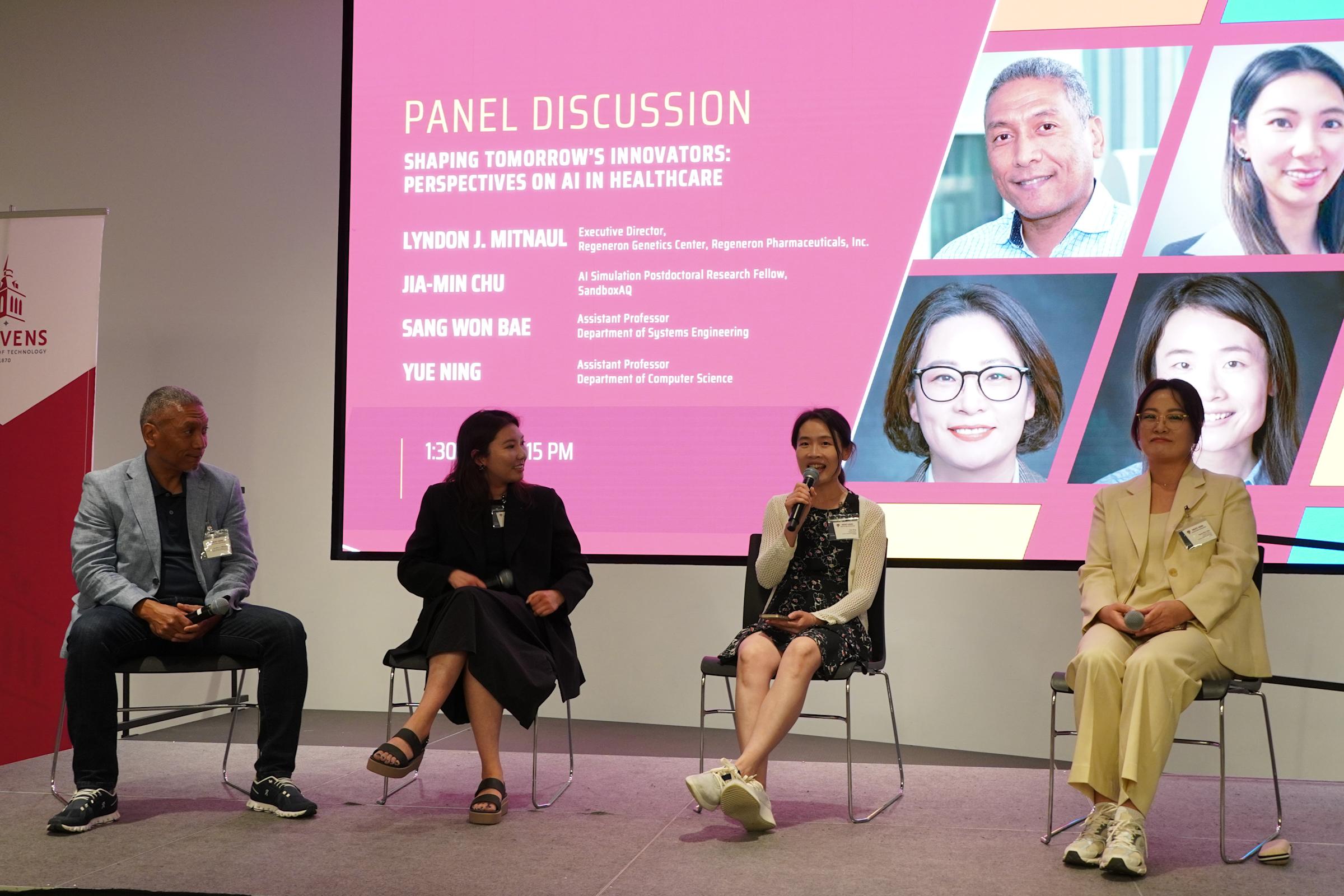 Lyndon J. Mitnaul, Jia-Min Chu, Yue Ning and Sang Won Bae sit on a stage in front of monitor displaying their credentials during a panel discussion.