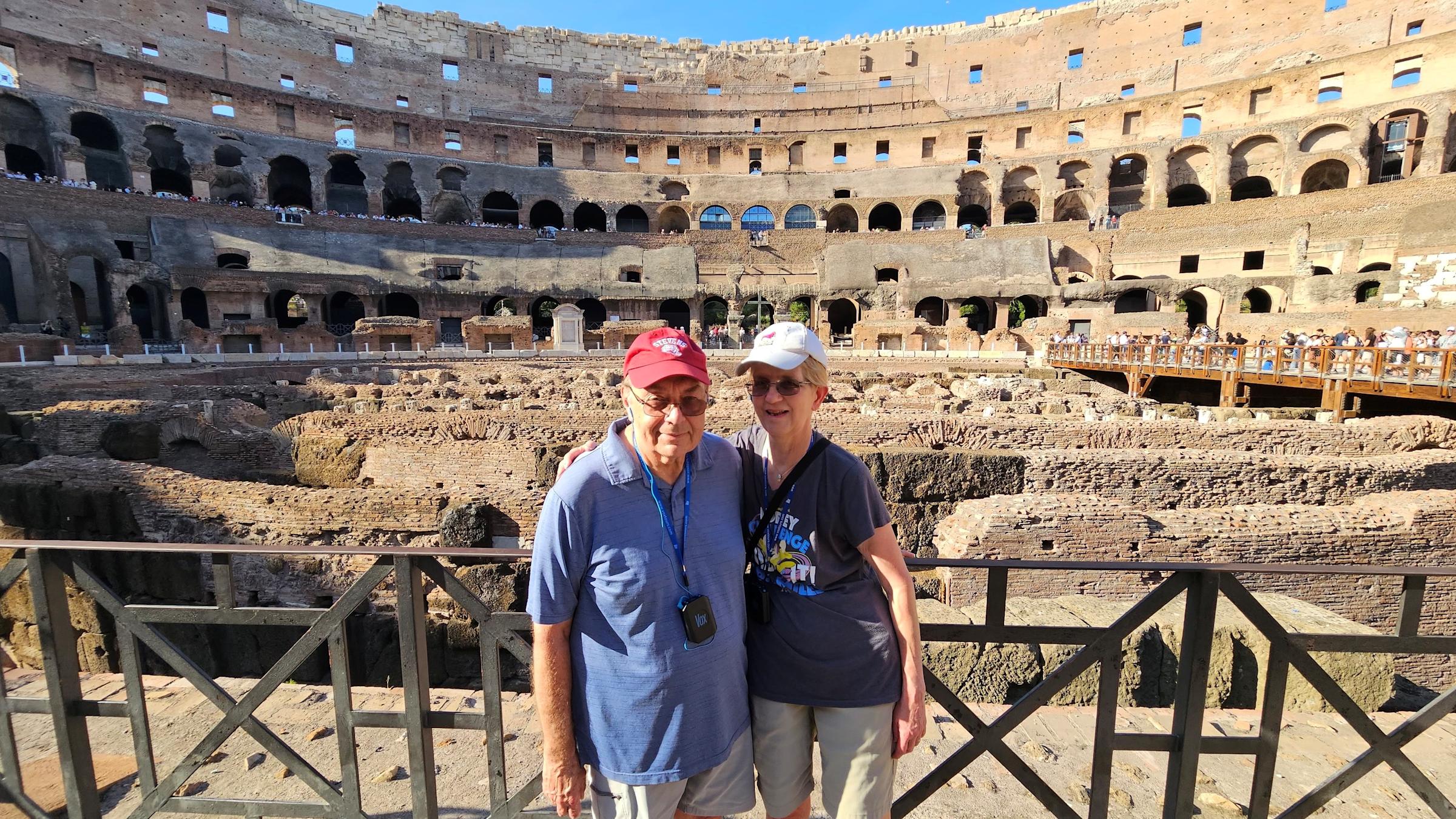 Barb and Jim Moraseski ’73 M.S. ’73 pose for picture together while in front of tourist destination of historical ruins, while Jim wears a Stevens baseball cap