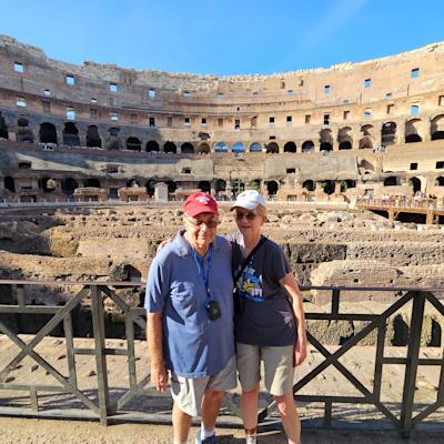 Barb and Jim Moraseski ’73 M.S. ’73 pose for picture together while in front of tourist destination of historical ruins, while Jim wears a Stevens baseball cap