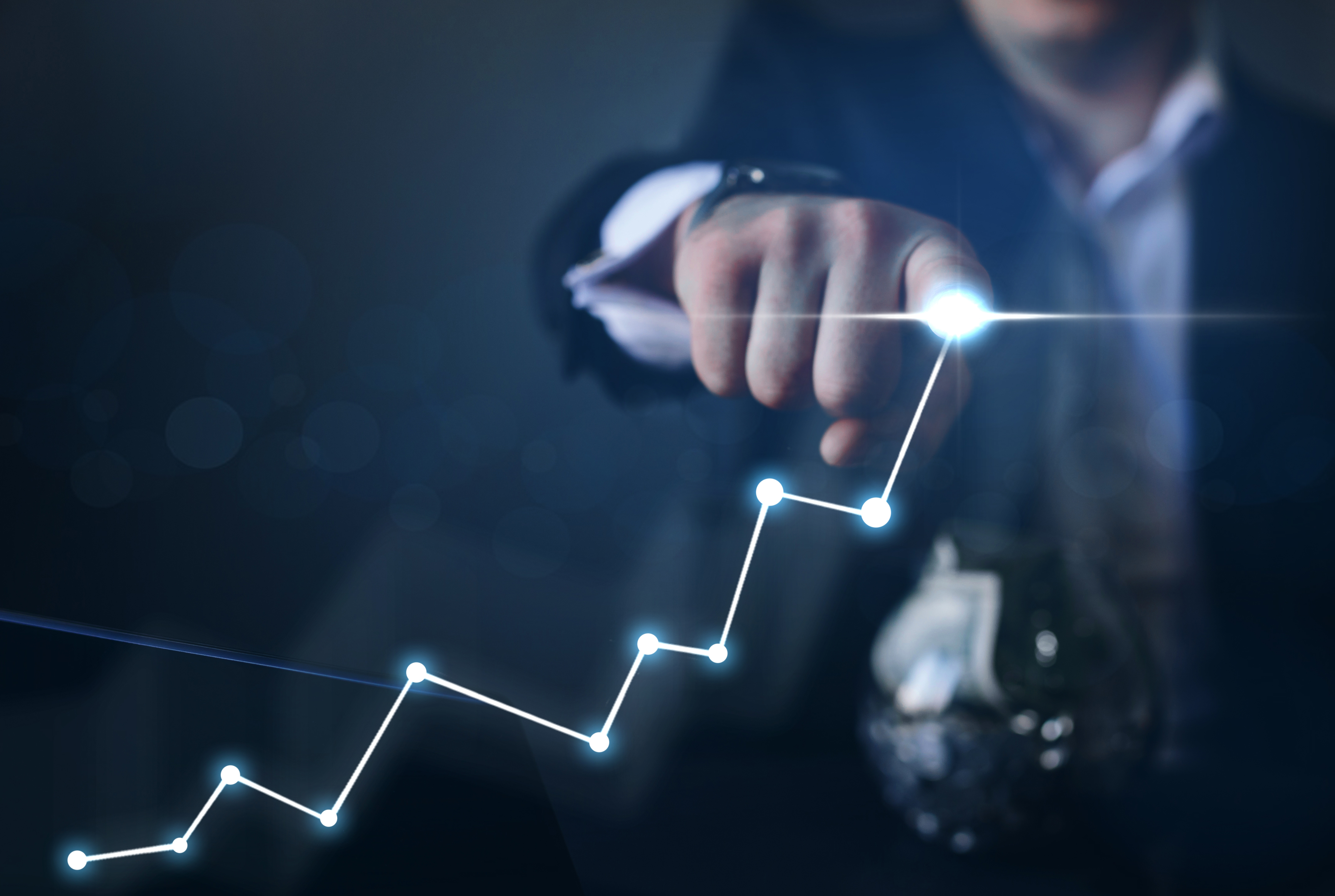 Man with glowing finger draws a line chart showing growth. 