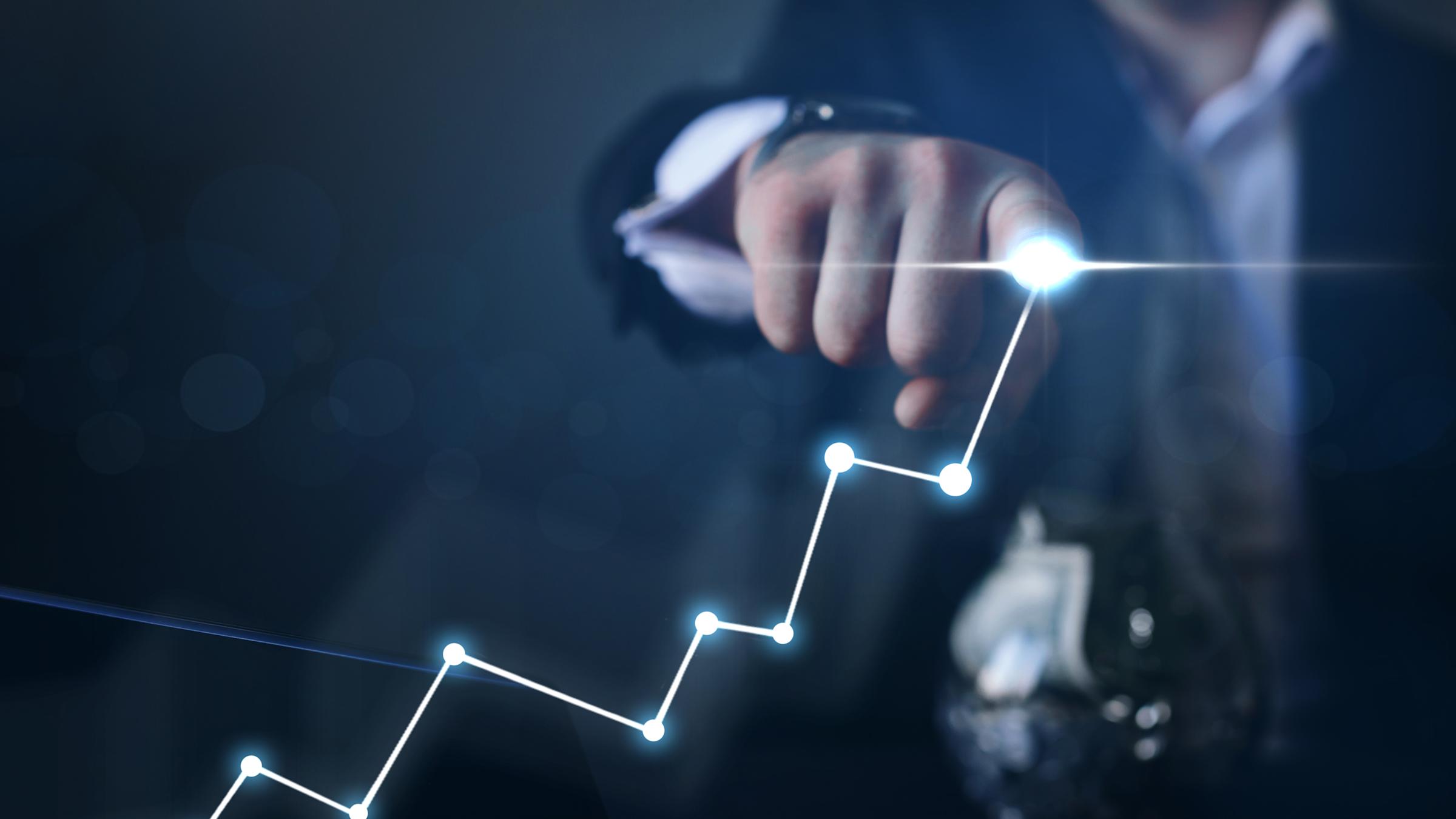 Man with glowing finger draws a line chart showing growth.