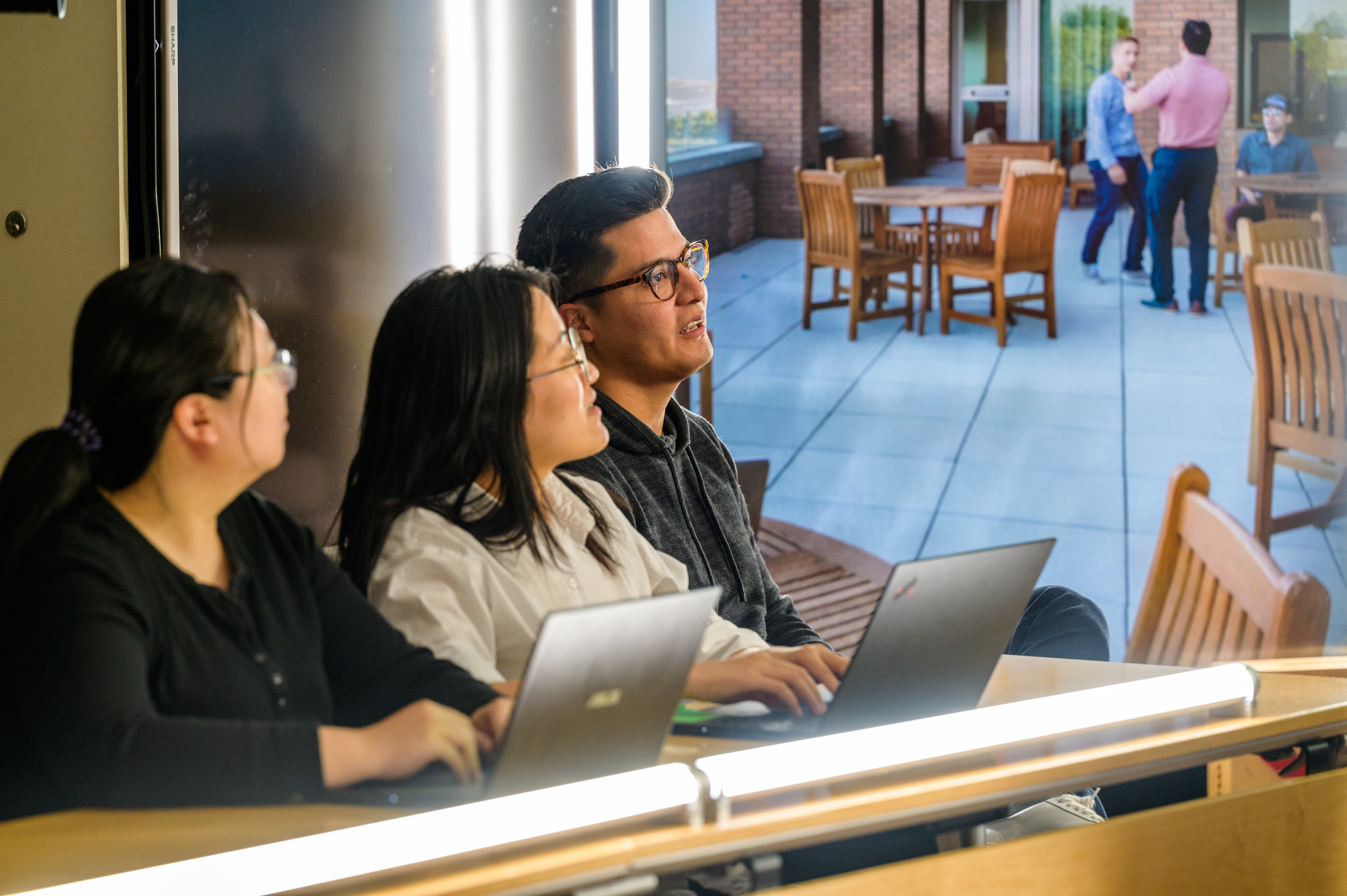 Three students listen intently to professor.