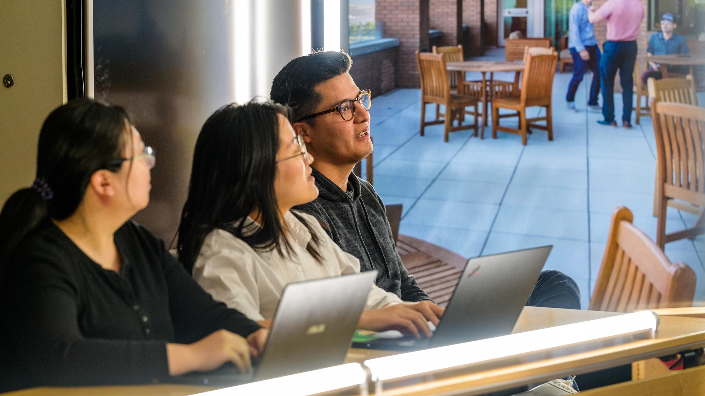Three students listen intently to professor.