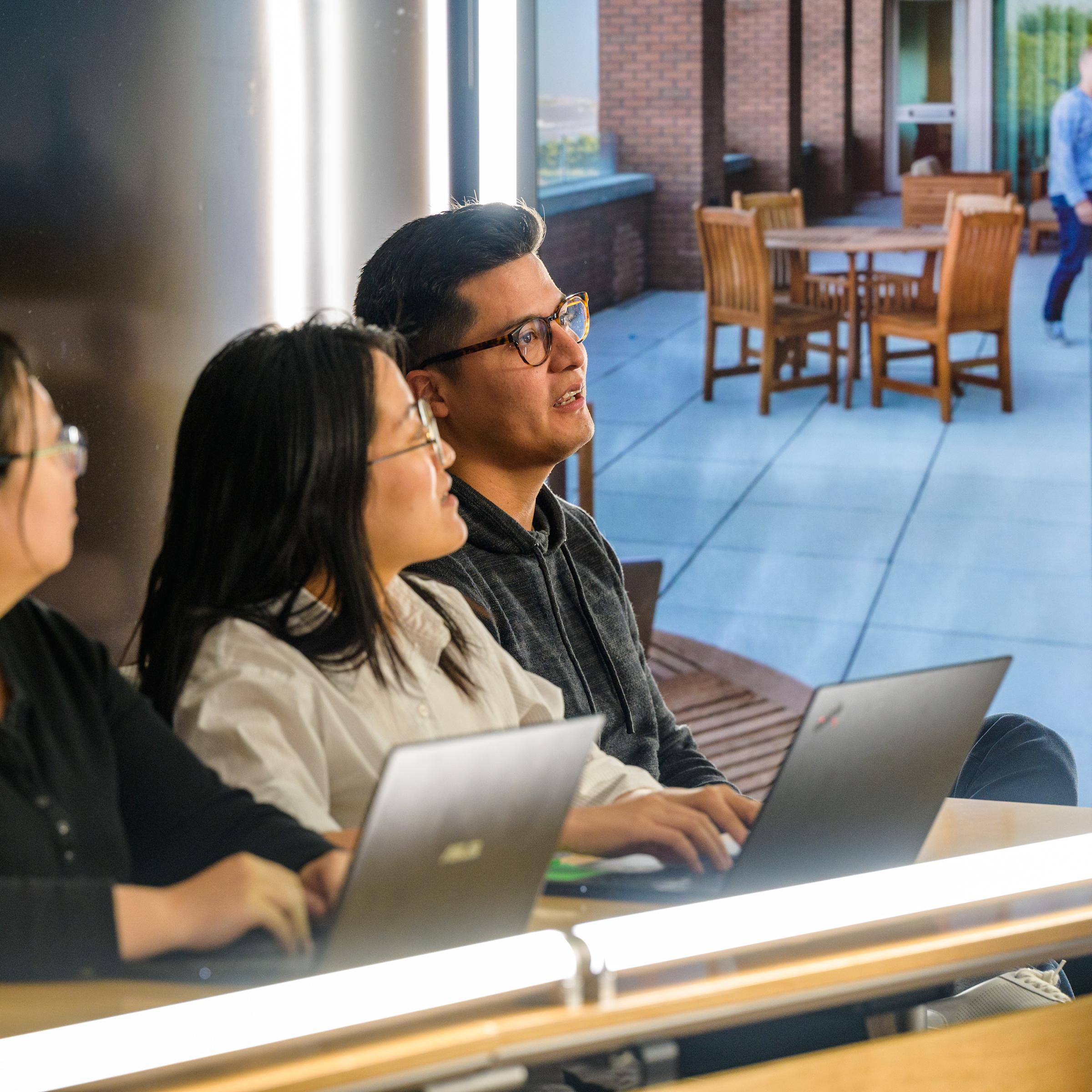 Three students listen intently to professor.