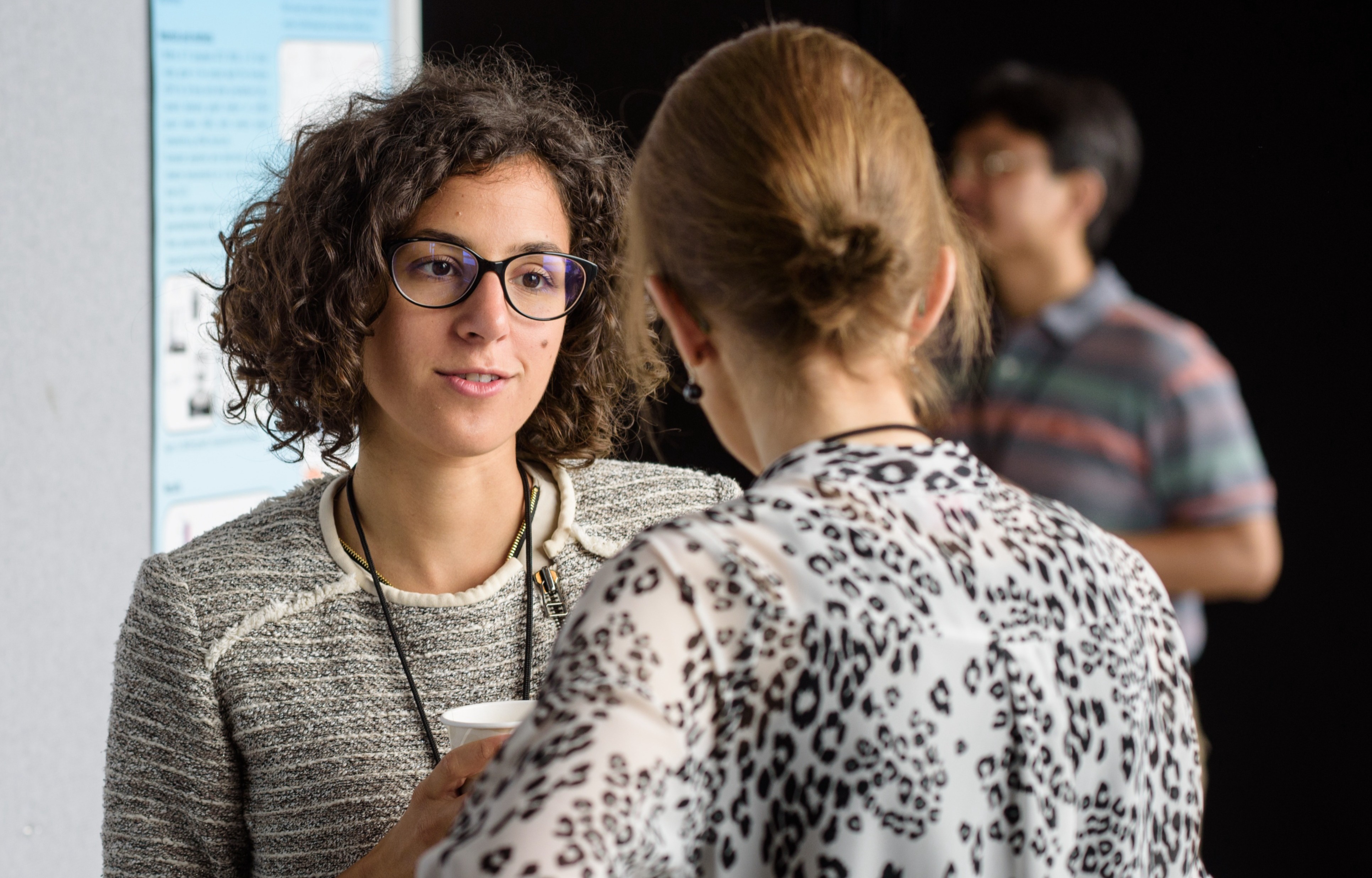 Female student at a poster session talking to a female professor.