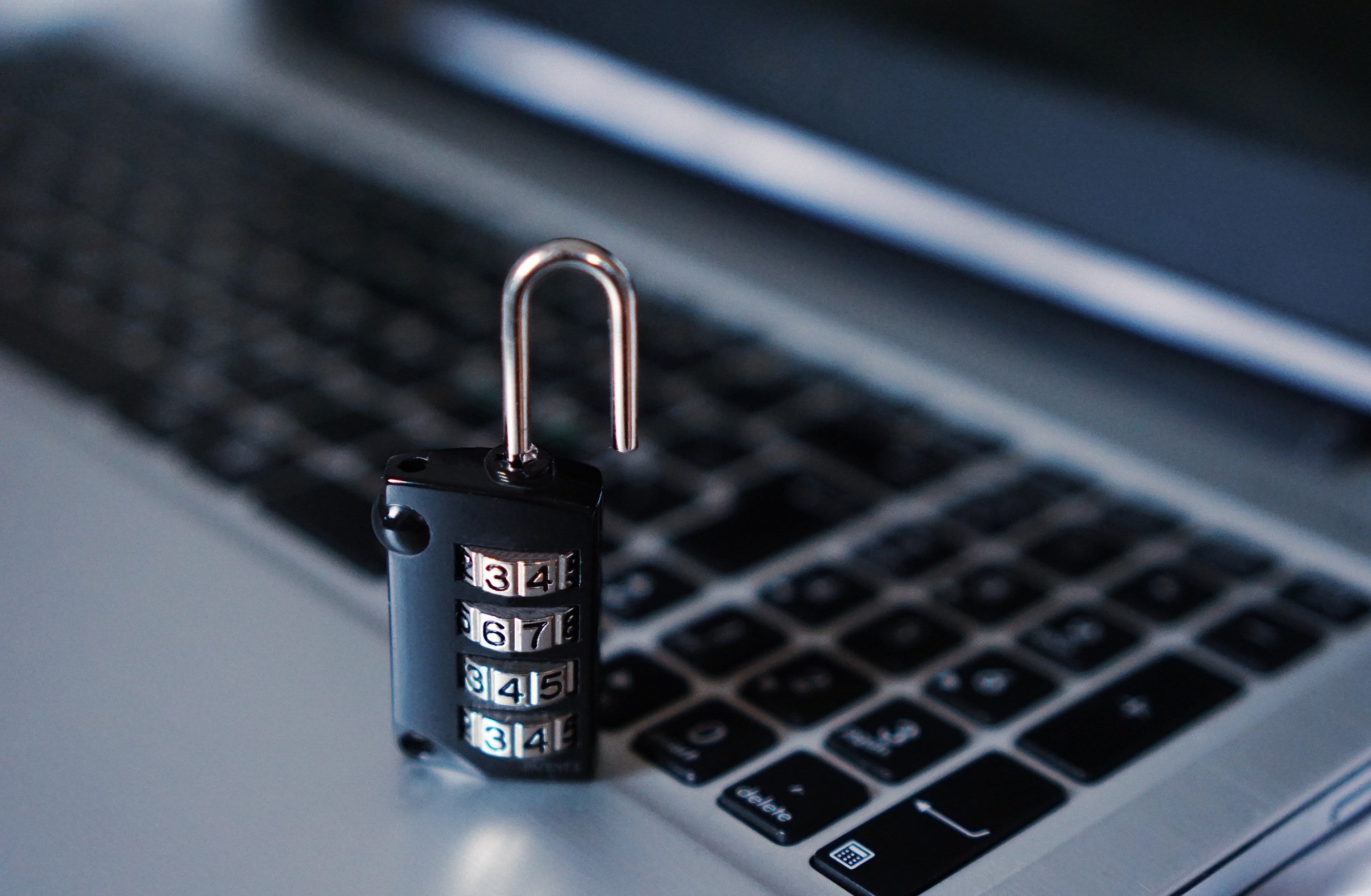 A stock image of an open lock in front a laptop keyboard.