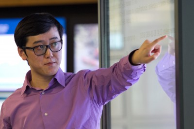 A professor pointing at a white screen