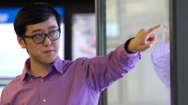 A professor pointing at a white screen