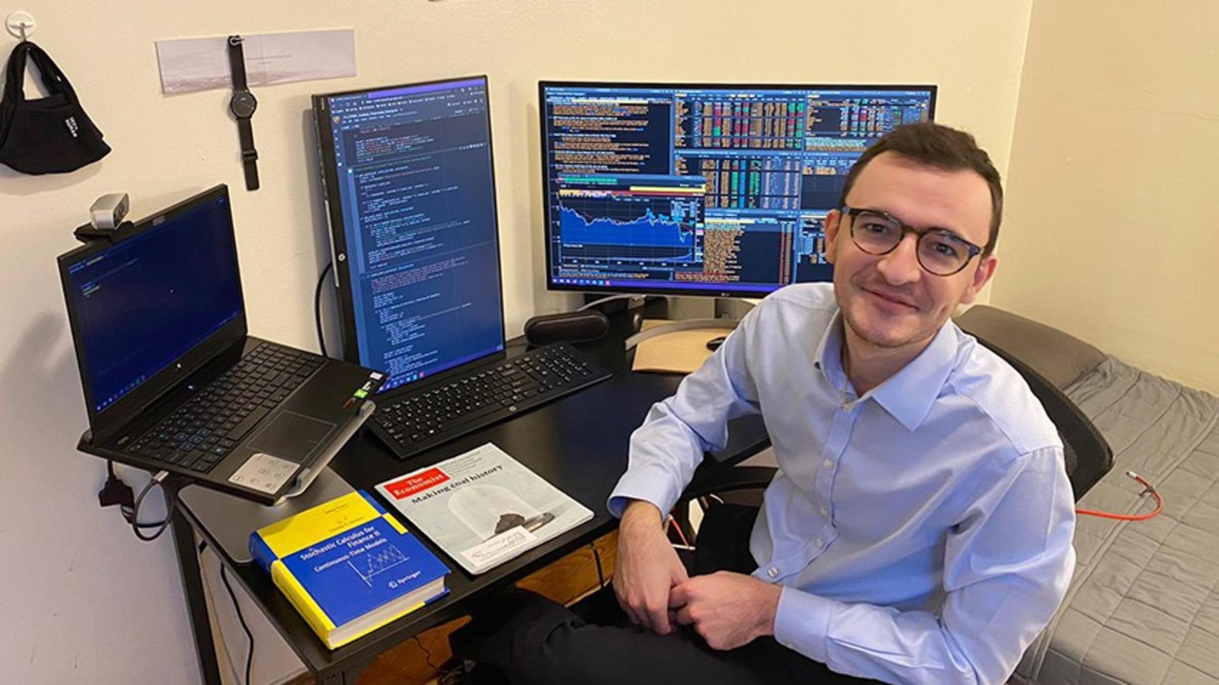 Theo Dimitrasopoulos in his home office. A Bloomberg ticker is running on the computer at his desk.