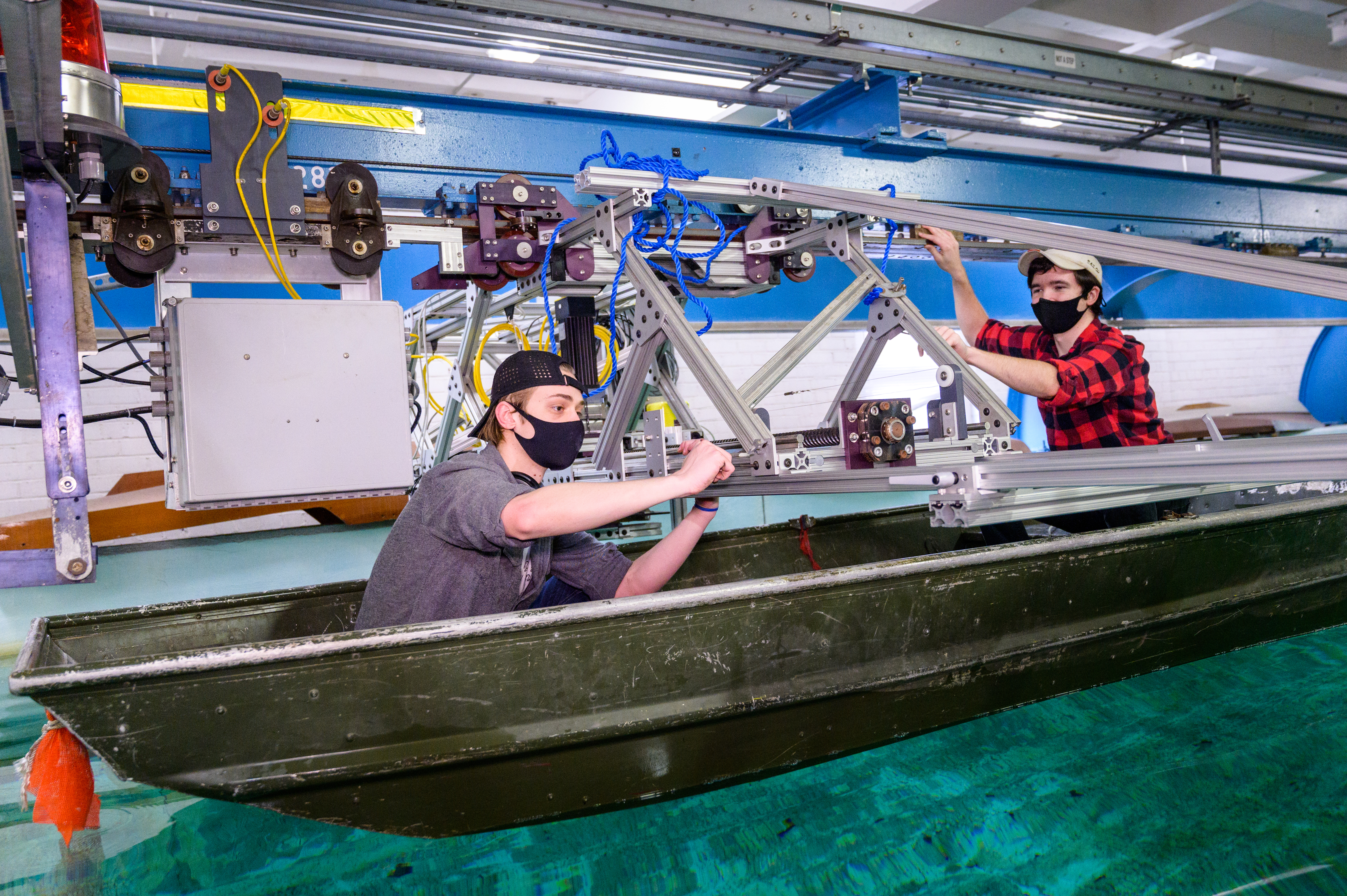 Students in boat in testing facility make adjustments