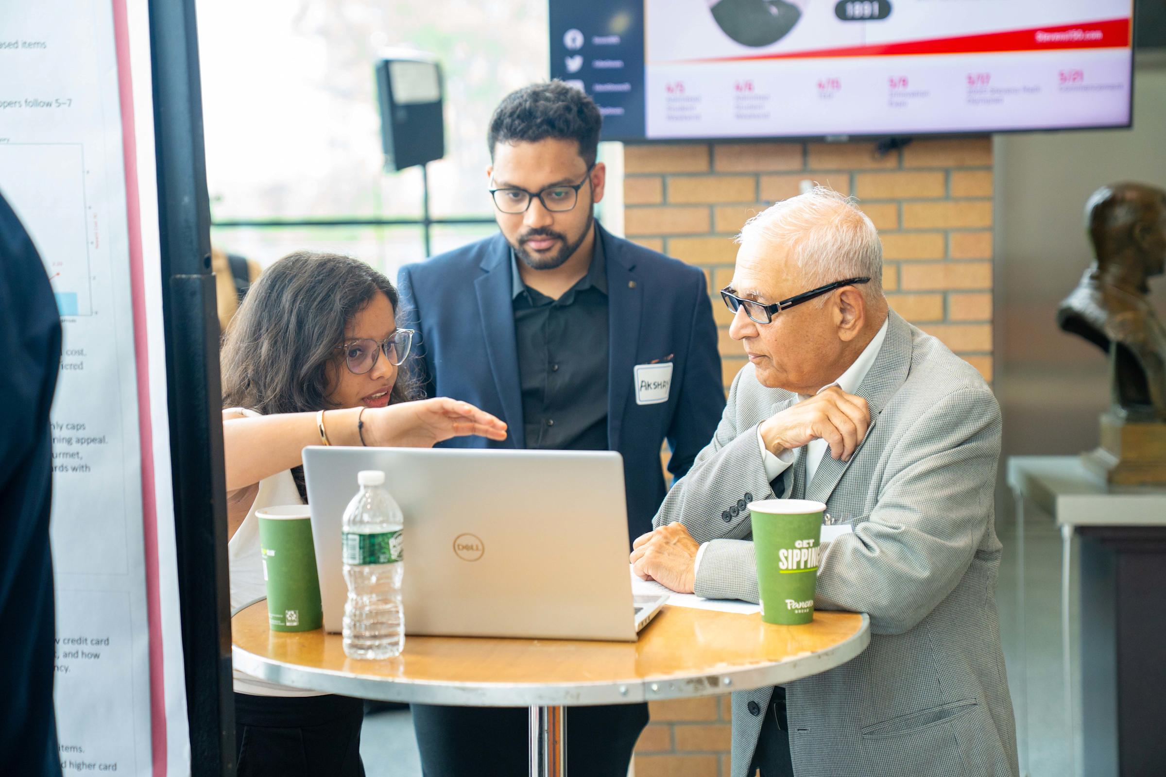 Student provides demonstration of research to two attendees