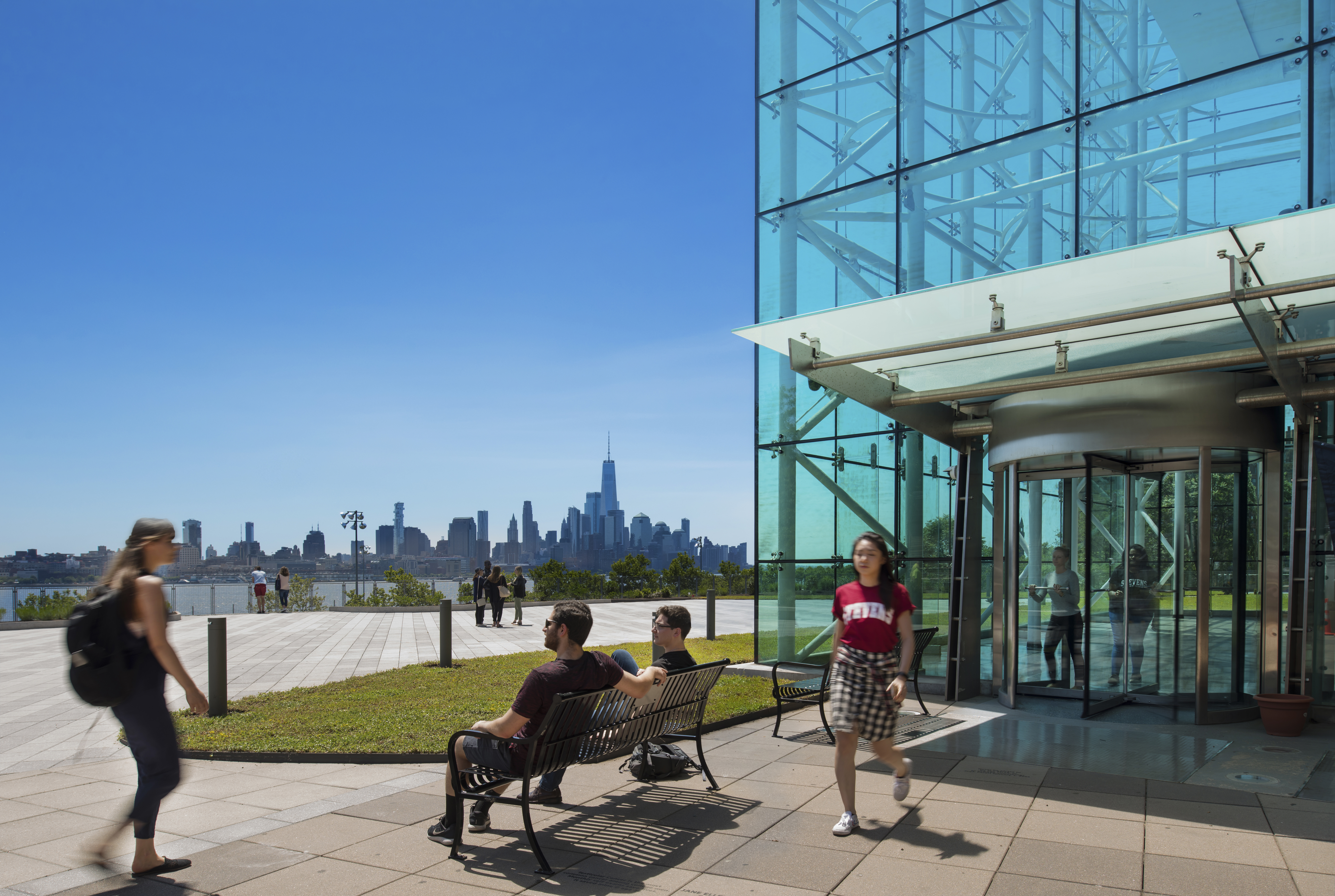 Students walk out of Babbio with skyline view of NYC in background