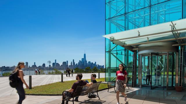 Students walk out of Babbio with skyline view of NYC in background