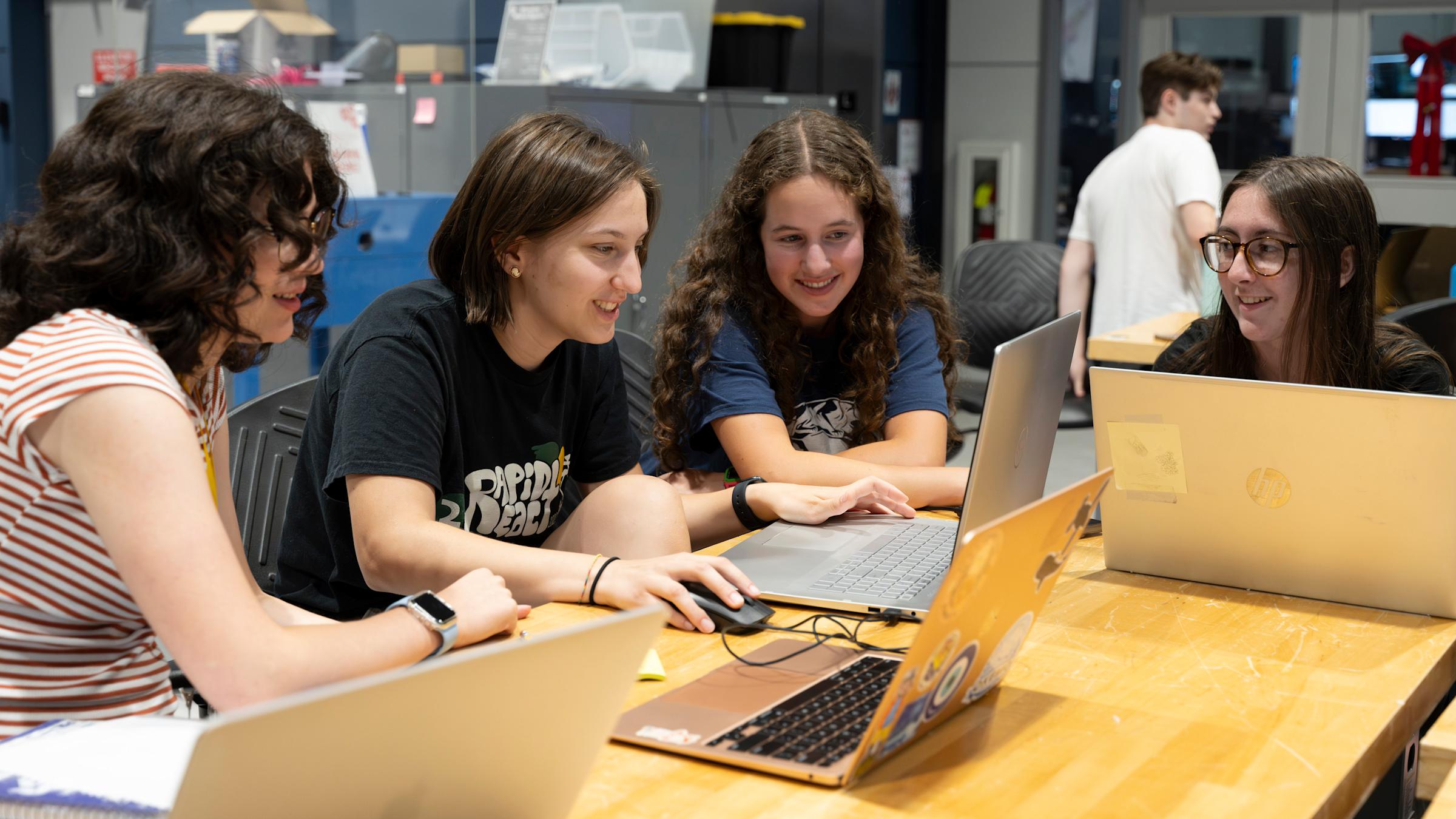 4 female students working on laptops