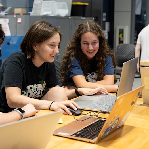 4 female students working on laptops