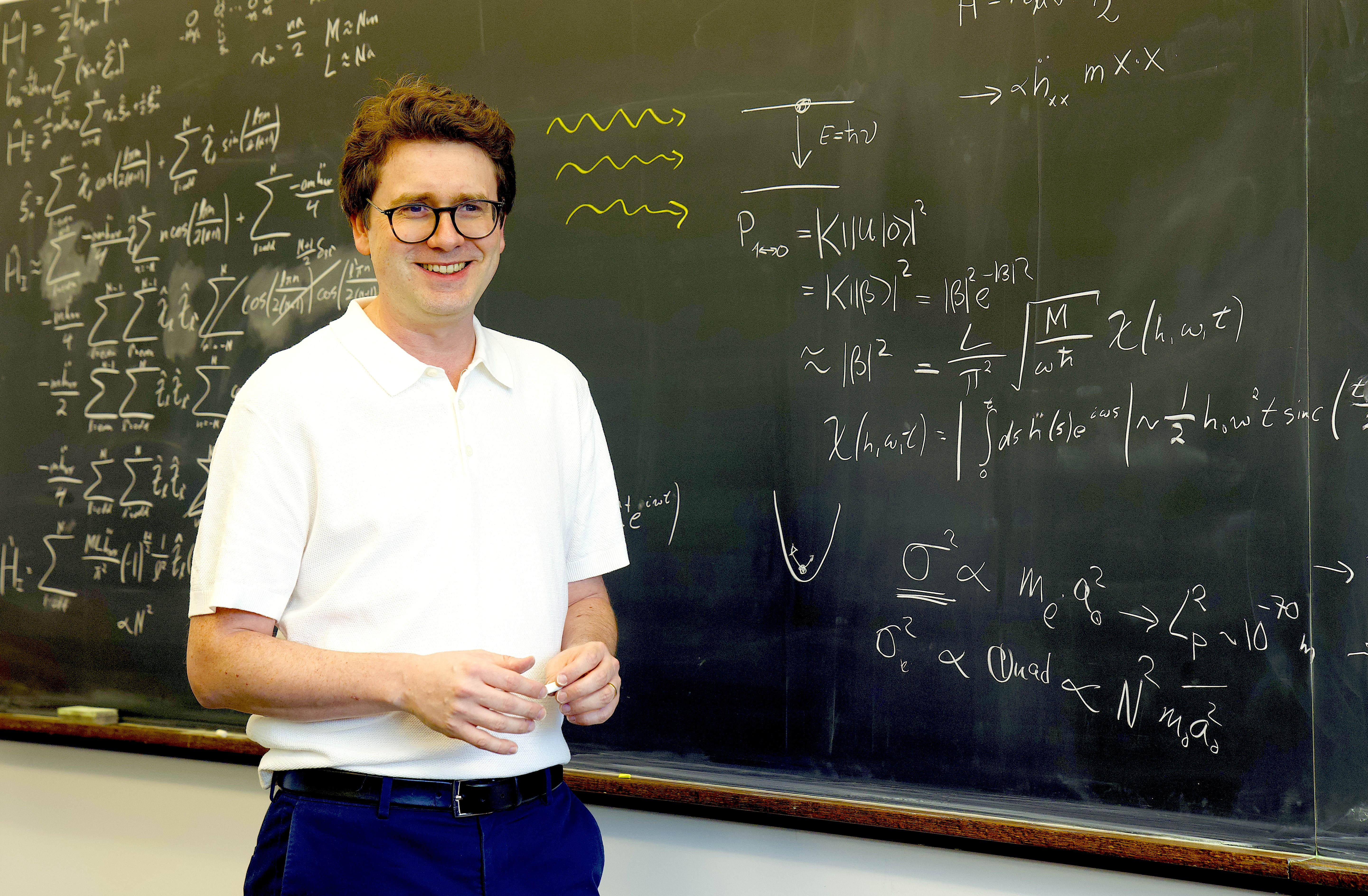Professor Igor Pikovski at a blackboard with equations written on it