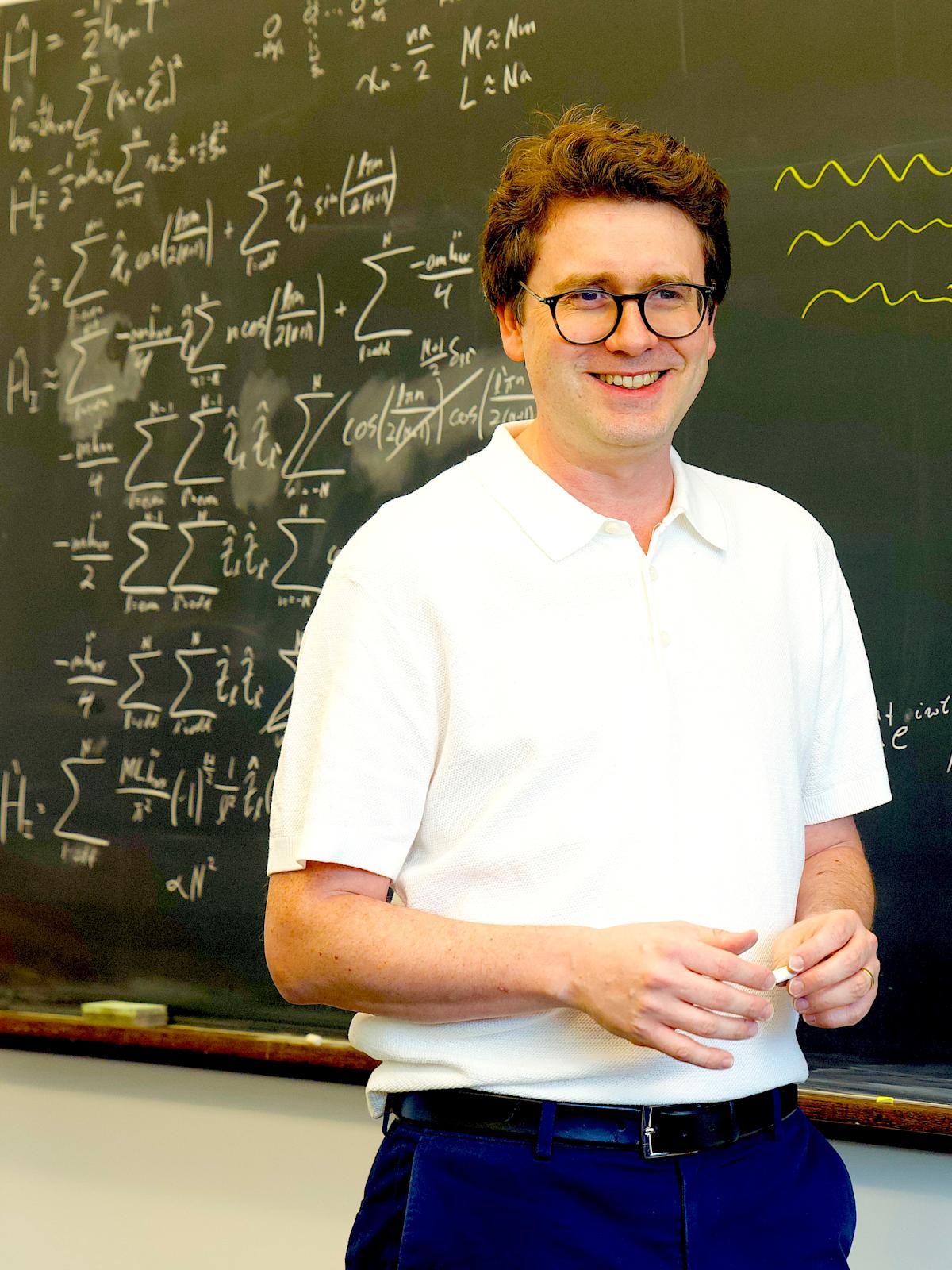 Professor Igor Pikovski at a blackboard with equations written on it