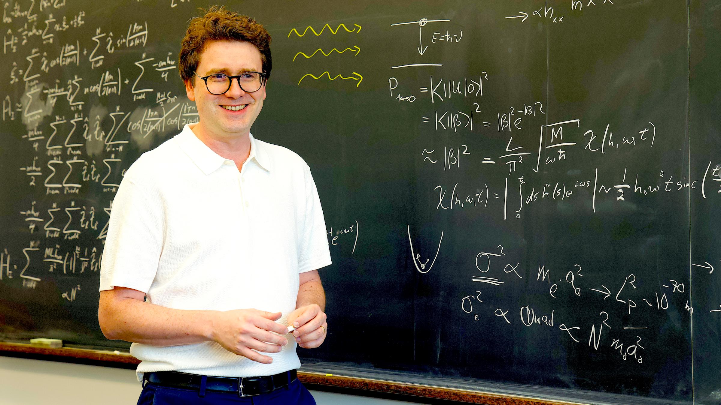 Professor Igor Pikovski at a blackboard with equations written on it