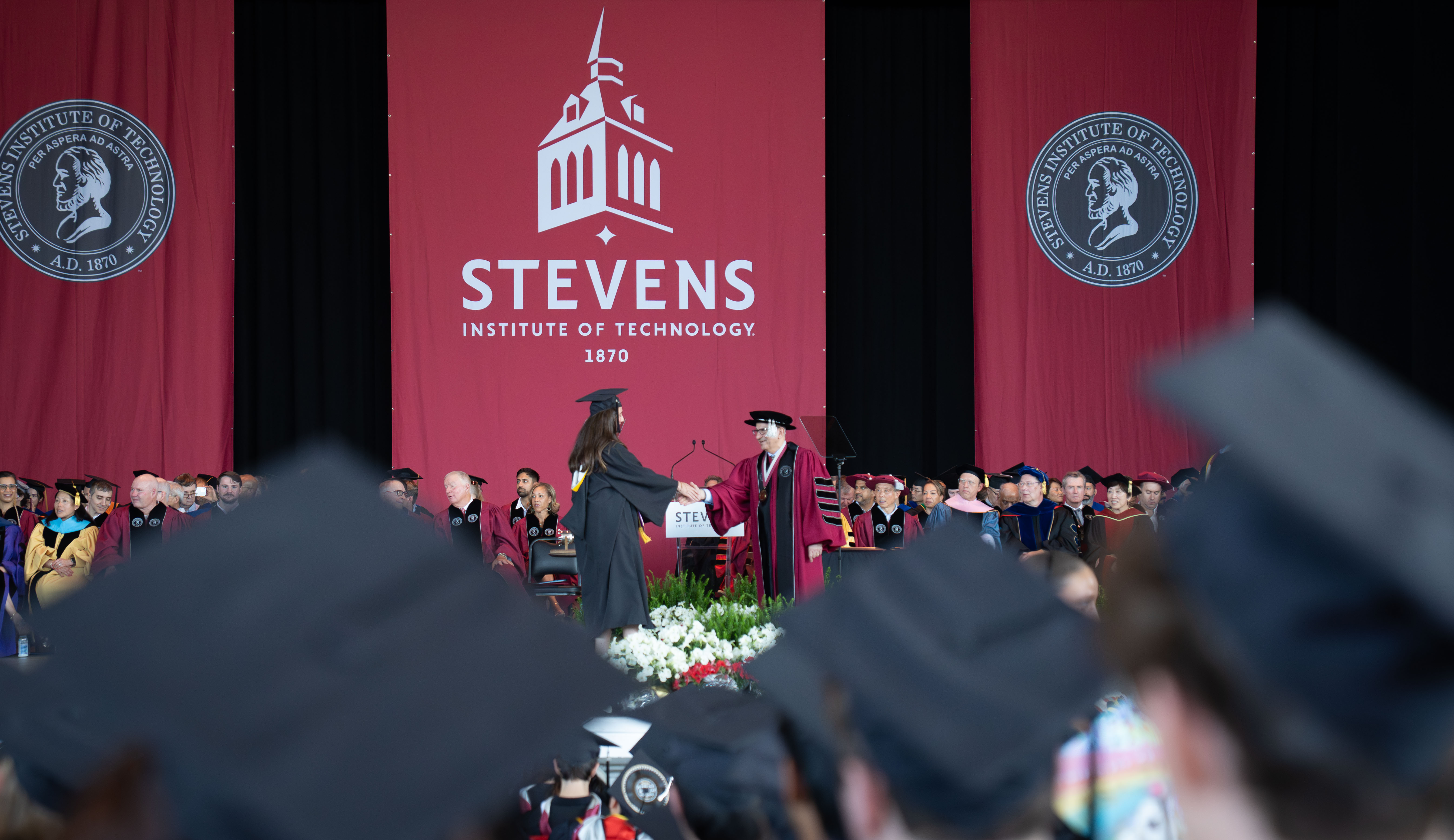 A 2026 School of Business graduate shakes hands with President Nariman Farvardin.
