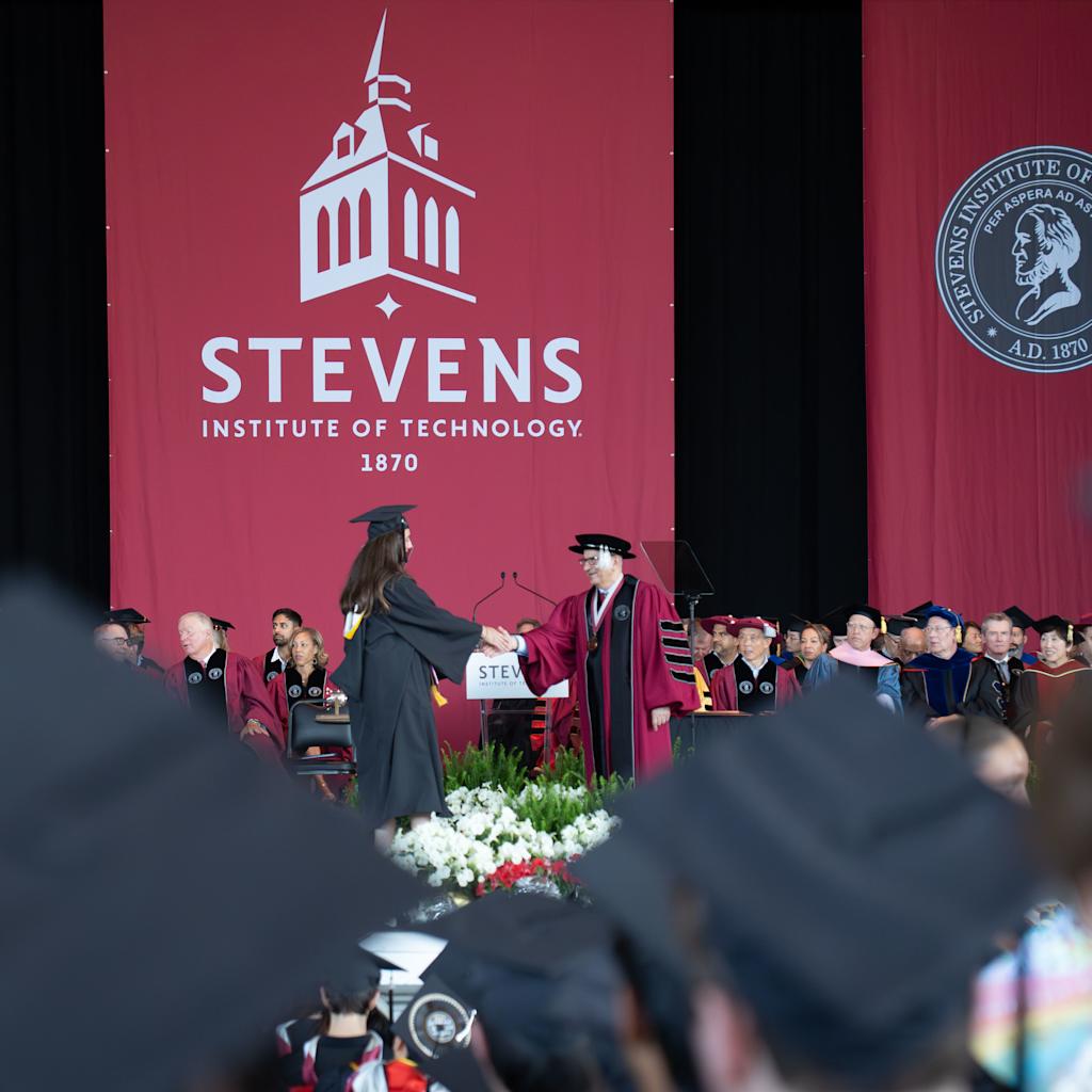 A 2026 School of Business graduate shakes hands with President Nariman Farvardin.