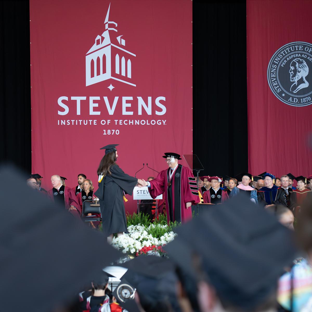 A 2026 School of Business graduate shakes hands with President Nariman Farvardin.