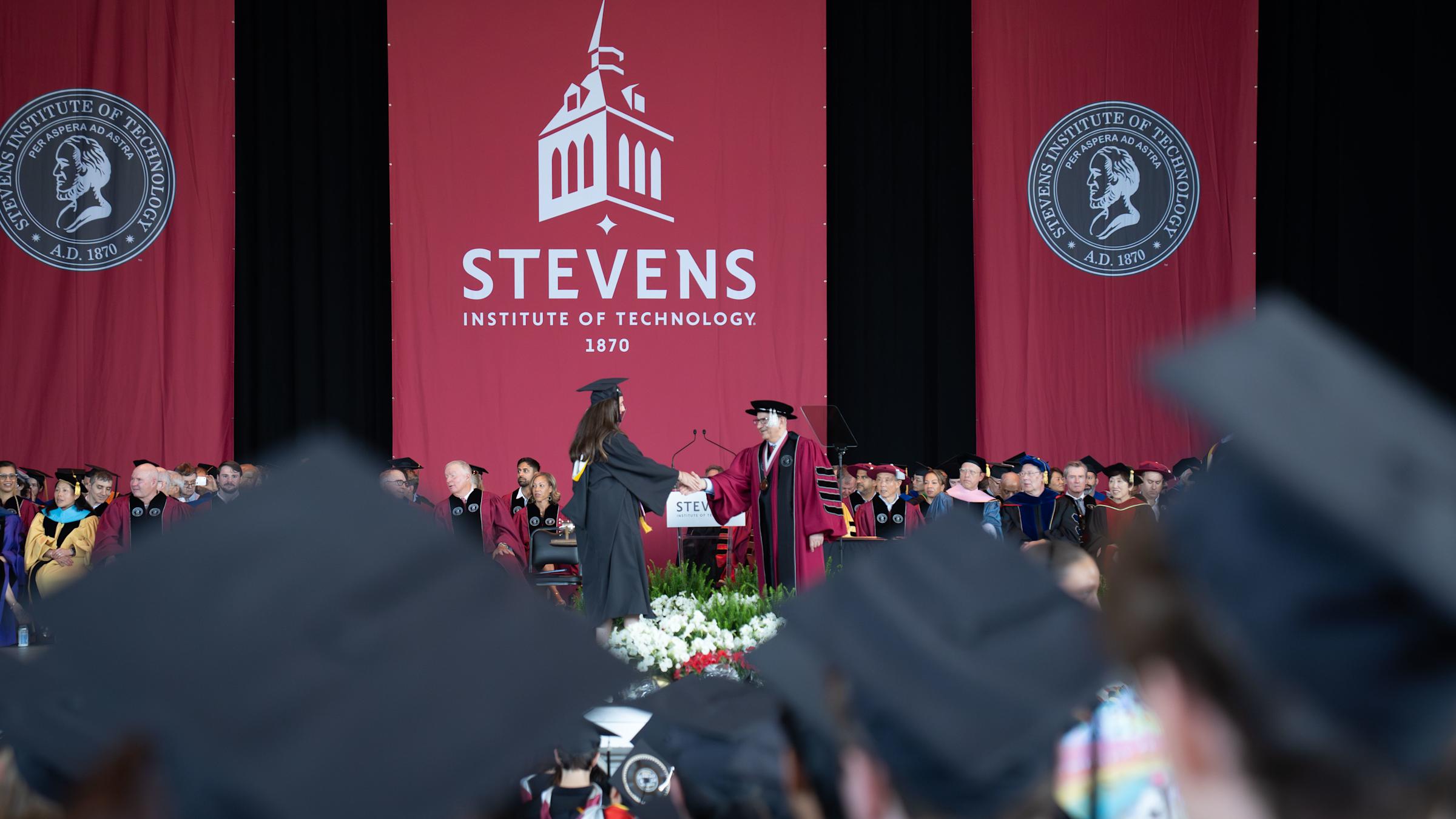 A 2026 School of Business graduate shakes hands with President Nariman Farvardin.