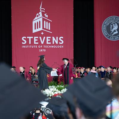 A 2026 School of Business graduate shakes hands with President Nariman Farvardin.