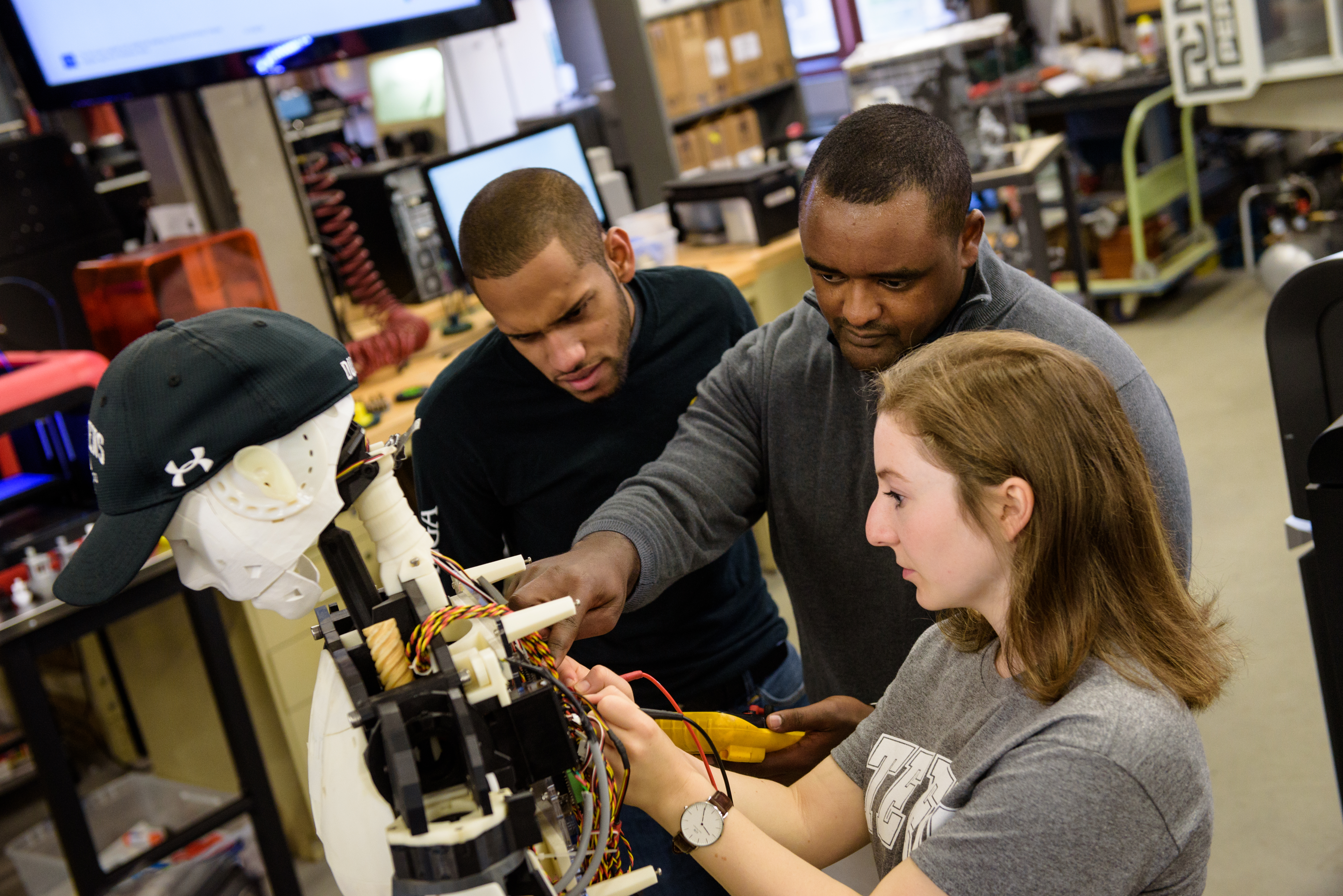 Faculty member and students working on a robot