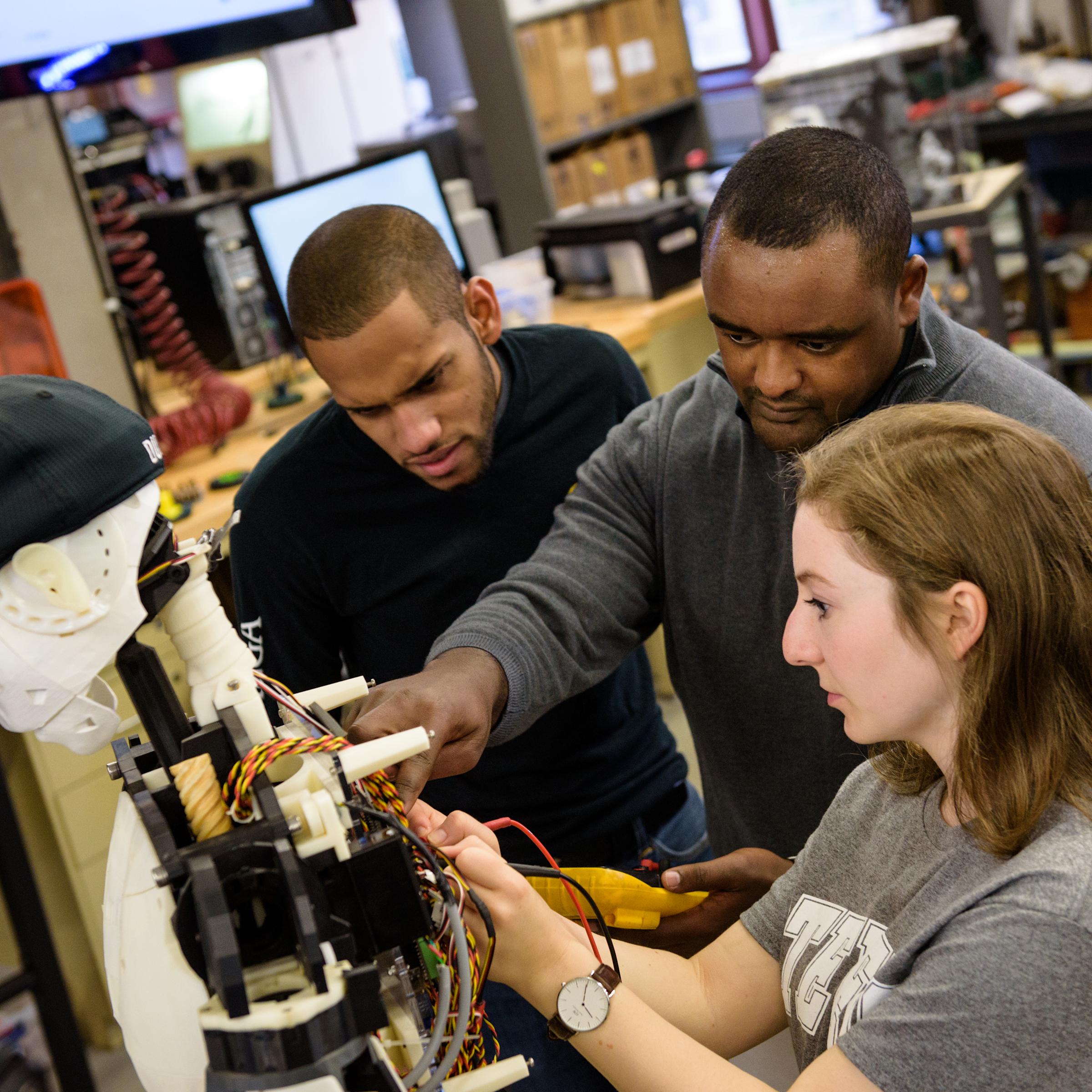 Faculty member and students working on a robot