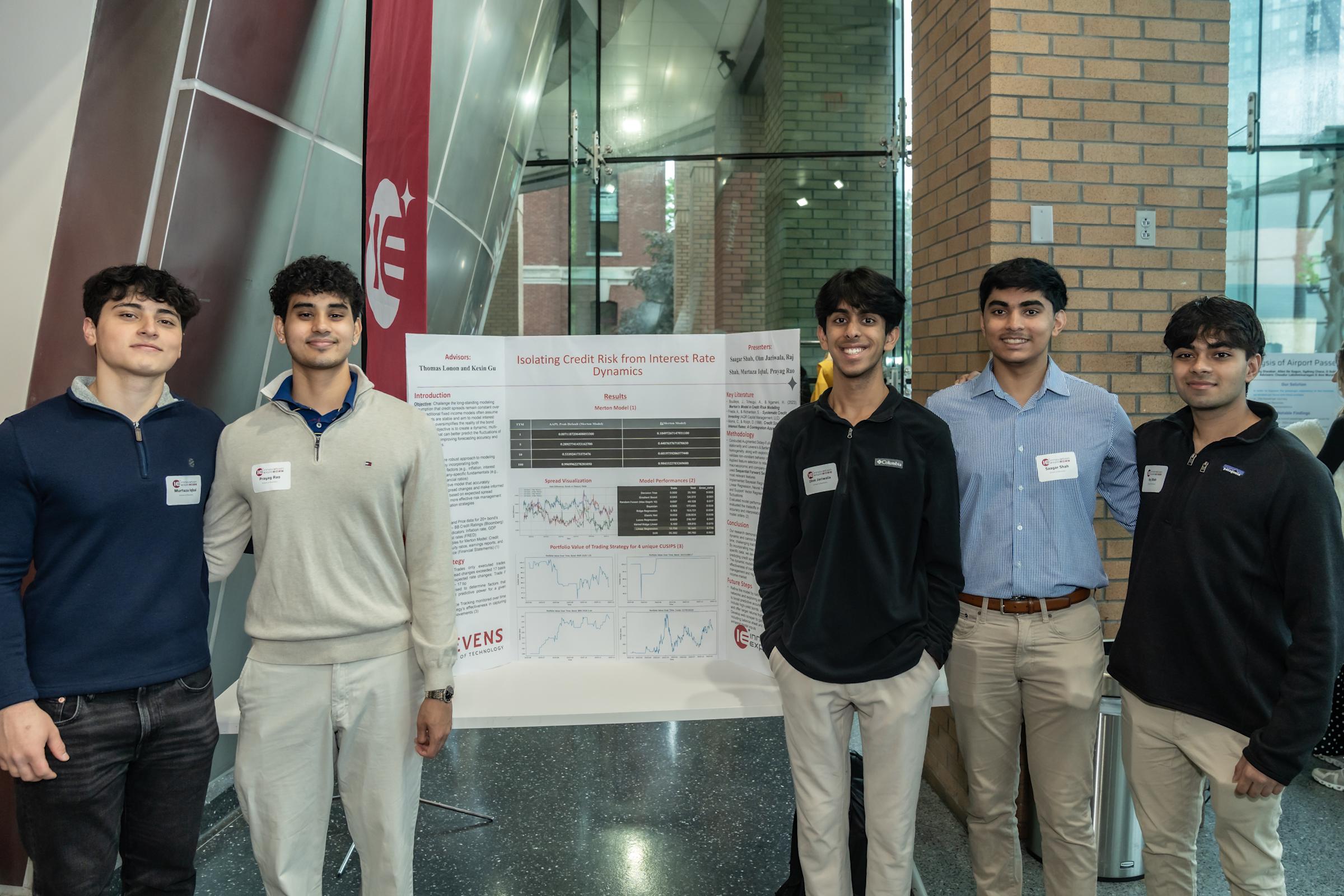 A team of five students pose in front of their project poster.