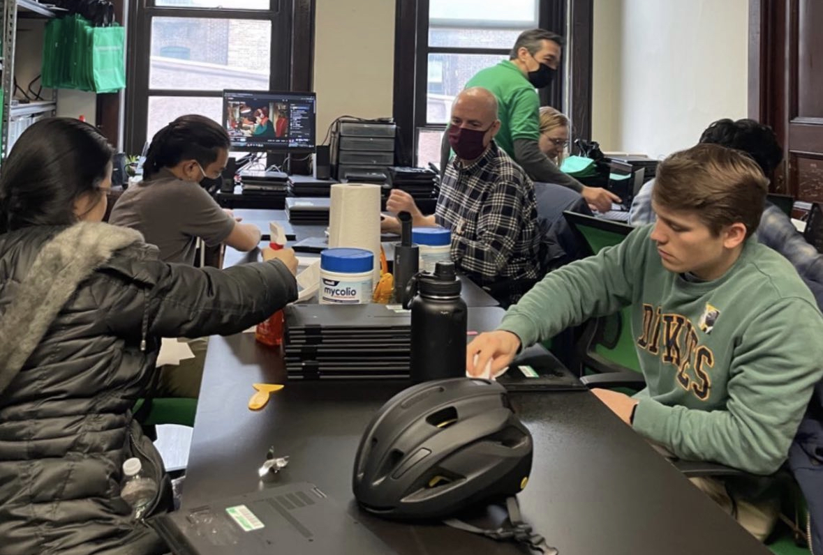 Student volunteers work on laptop computers in an IT lab.