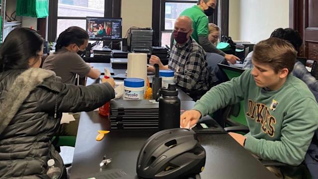 Student volunteers work on laptop computers in an IT lab.