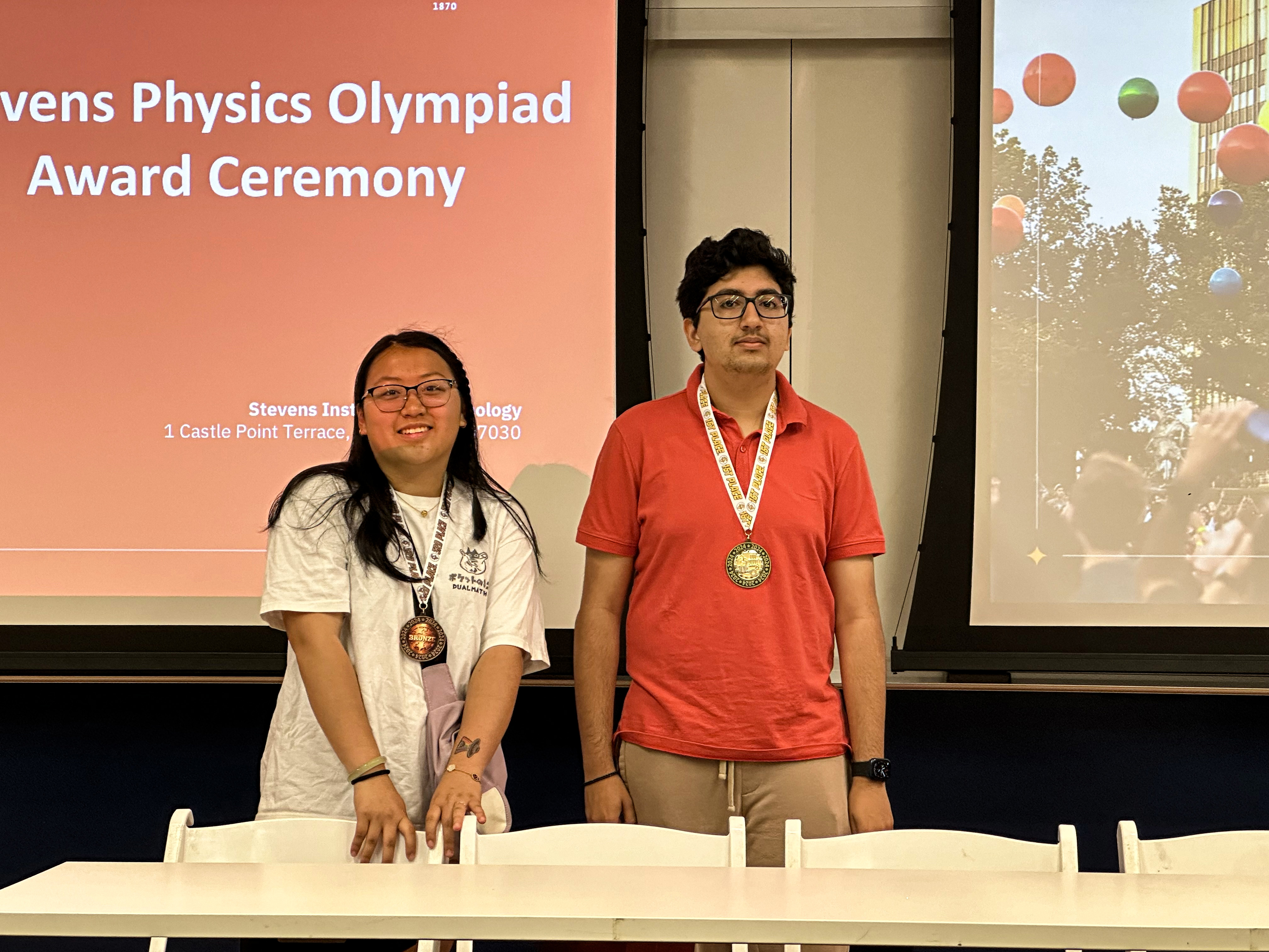 Two of the winners from the 2024 Physics Olympiad smiling with their medals.