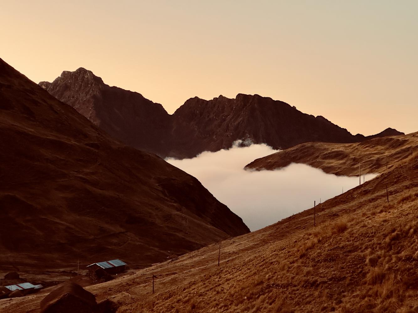 A view of a mountain range at either sunset or sunrise. A mist rises from the vallery below.