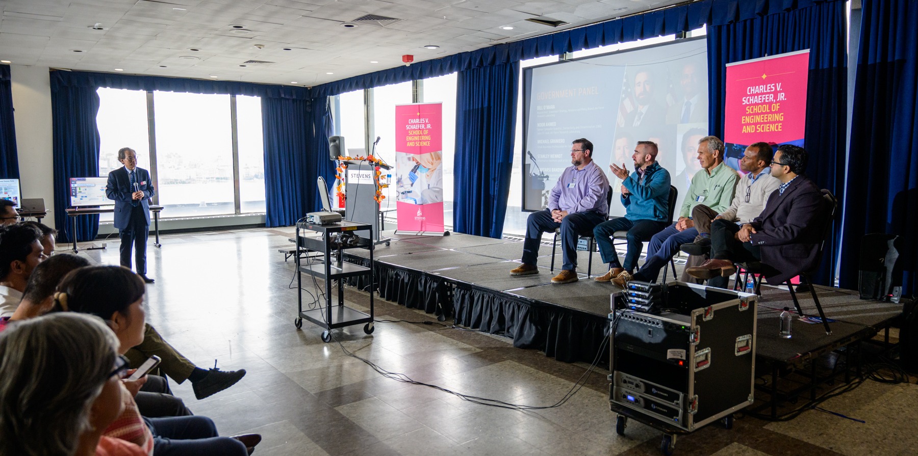 Professor Min Song moderating a panel of five speakers on stage.