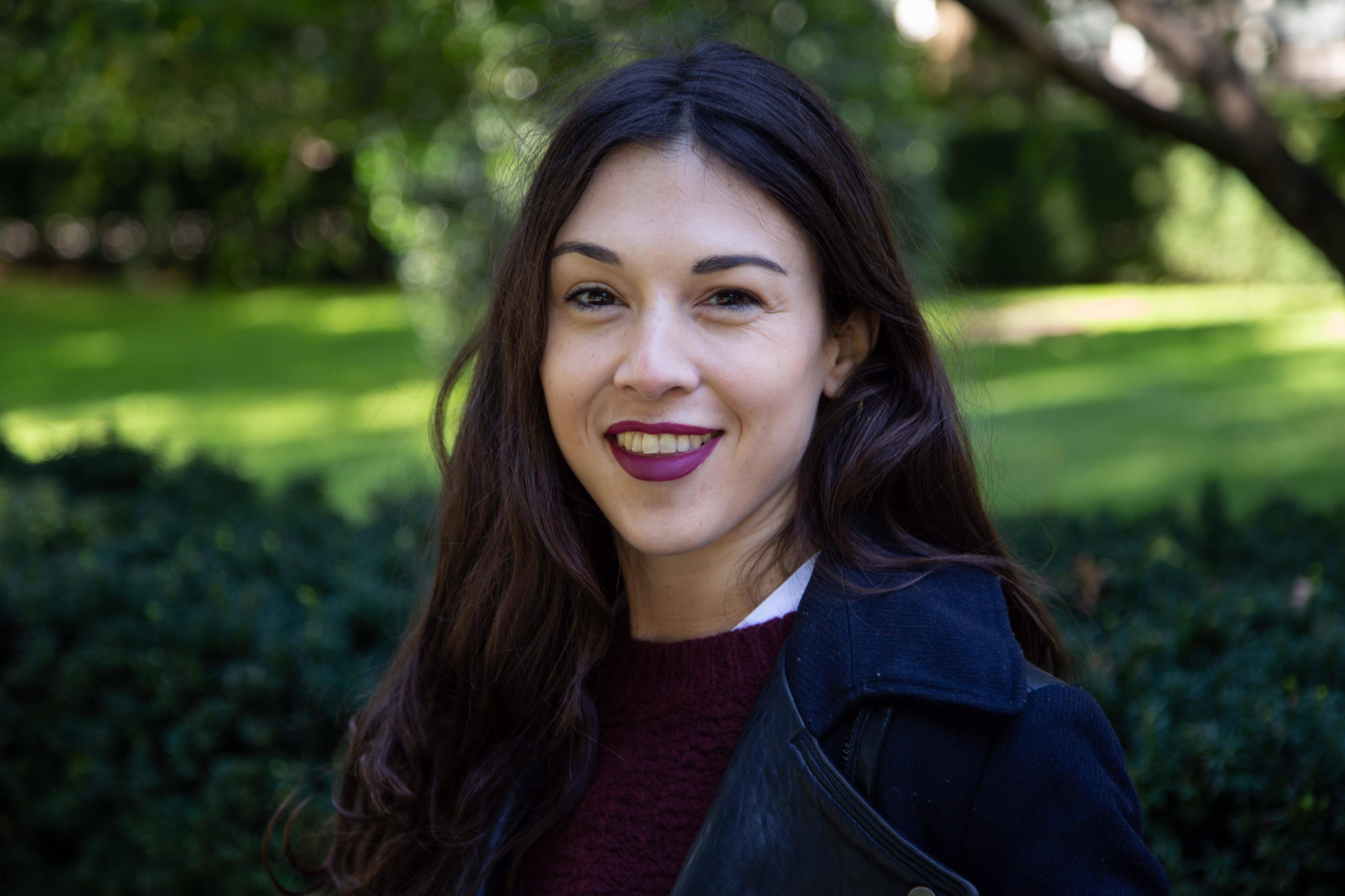 Head and shoulders portrait of Justine Herve with the hedges and a lawn as the background.