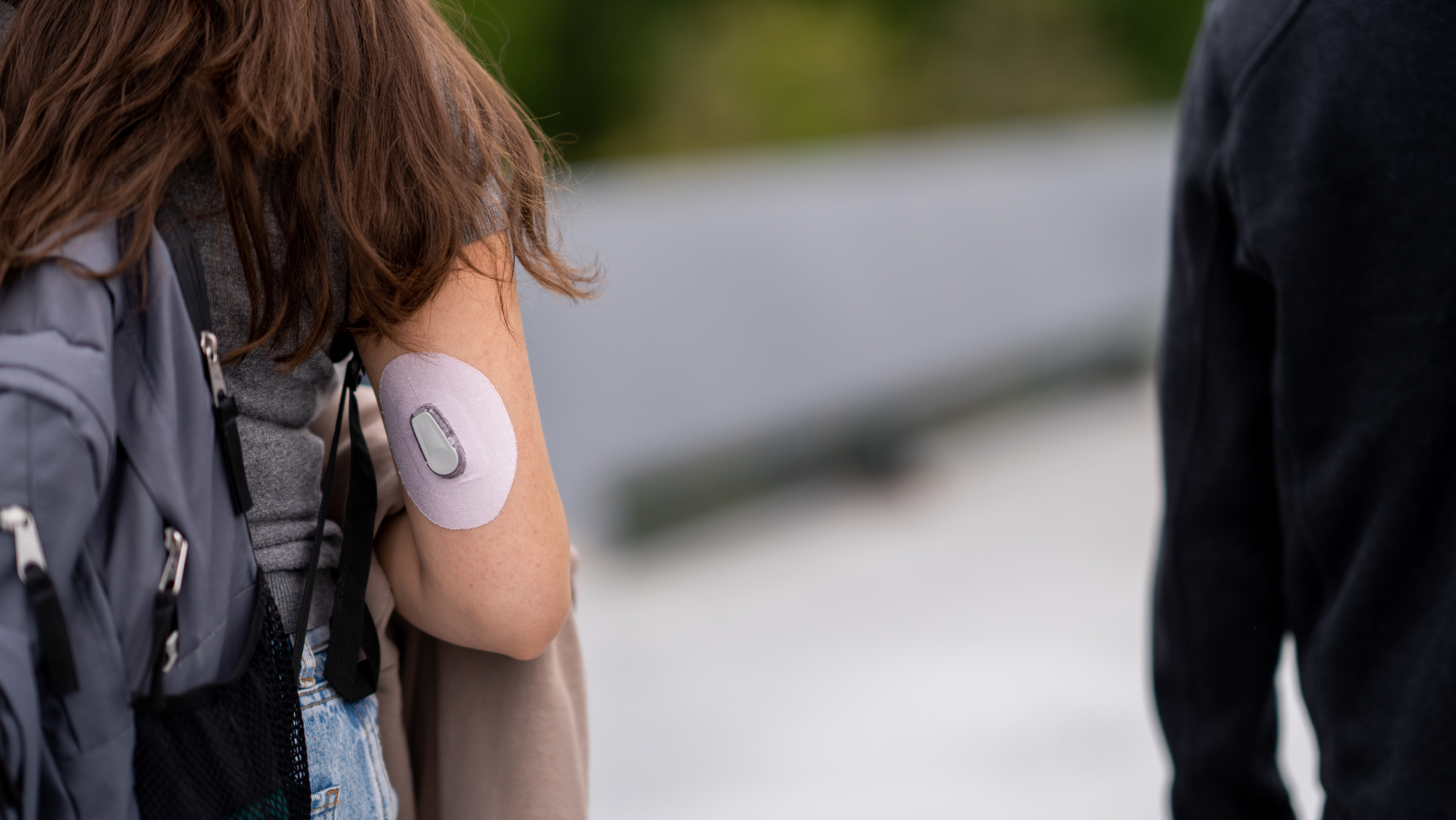 Back of student wearing backpack and glucose monitor on back of arm