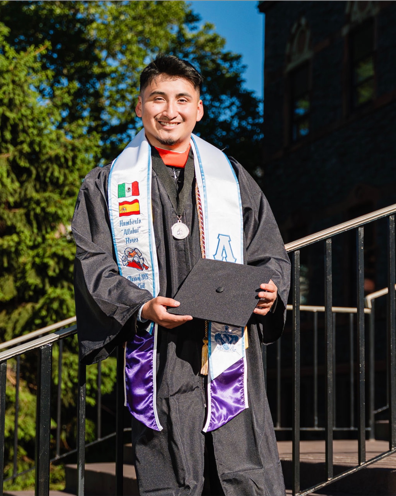 Humberto Flores ’25 smiles in graduation regalia with Stevens degree