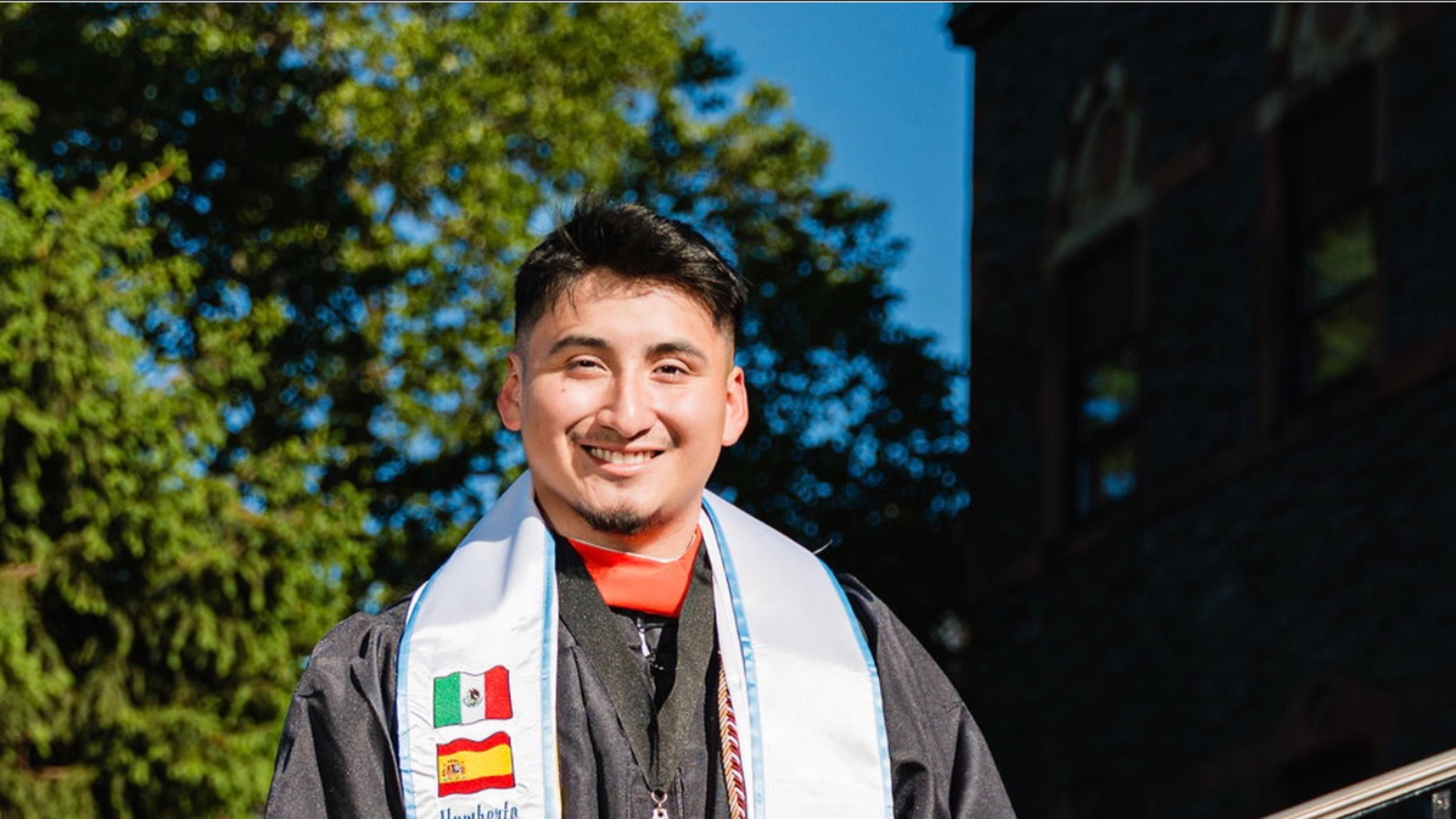 Humberto Flores ’25 smiles in graduation regalia with Stevens degree
