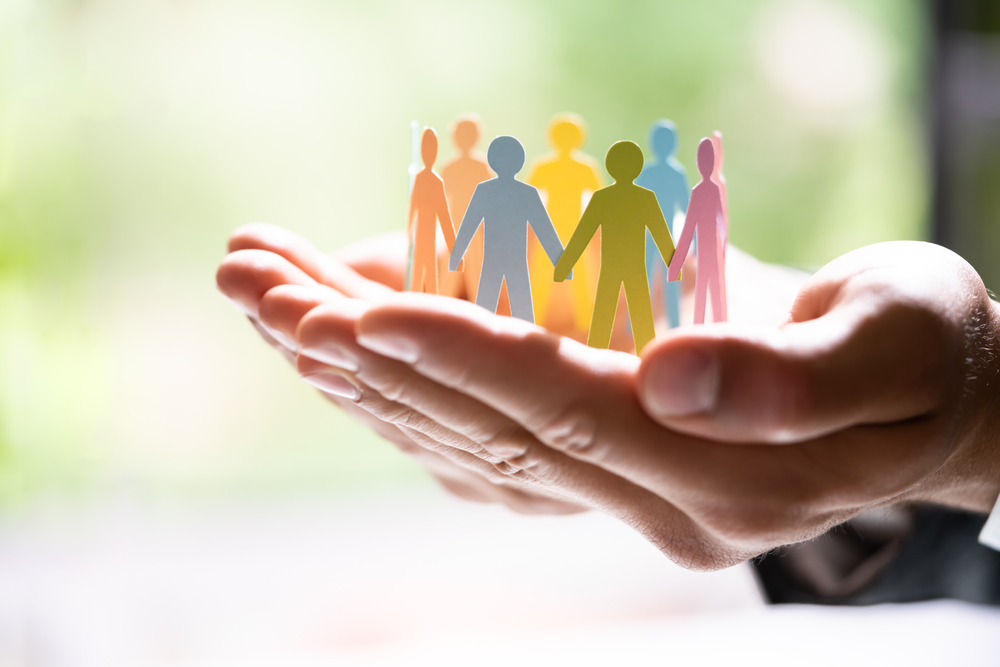 Human hand holds cutout silhouettes of people