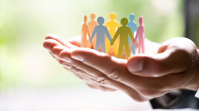 Human hand holds cutout silhouettes of people